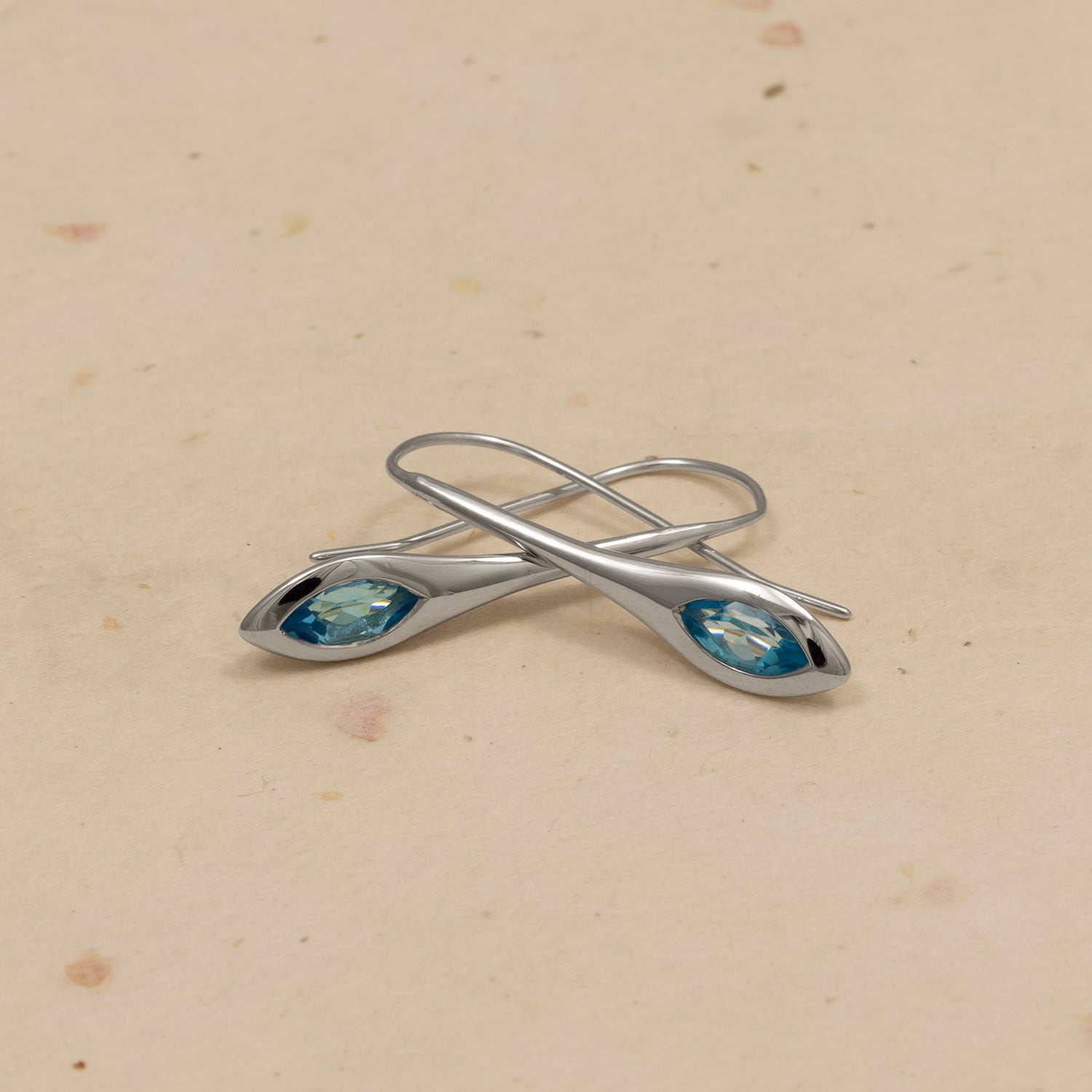 Pair of sterling silver drop earrings featuring elongated marquise-shaped settings with sparkling Swiss blue topaz gemstones, showcasing elegant and contemporary silver jewellery design.