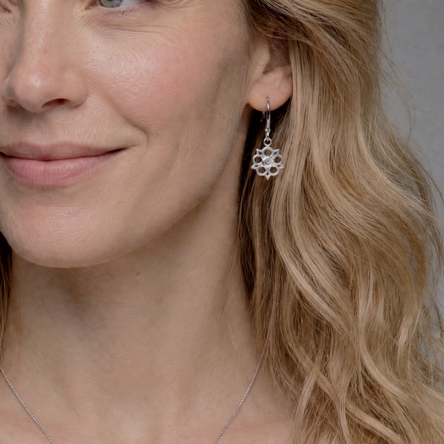 Model wears delicate sterling silver drop earrings featuring an openwork Yorkshire rose motif with a central lab-grown diamond, combining elegant floral design with contemporary silver jewellery.