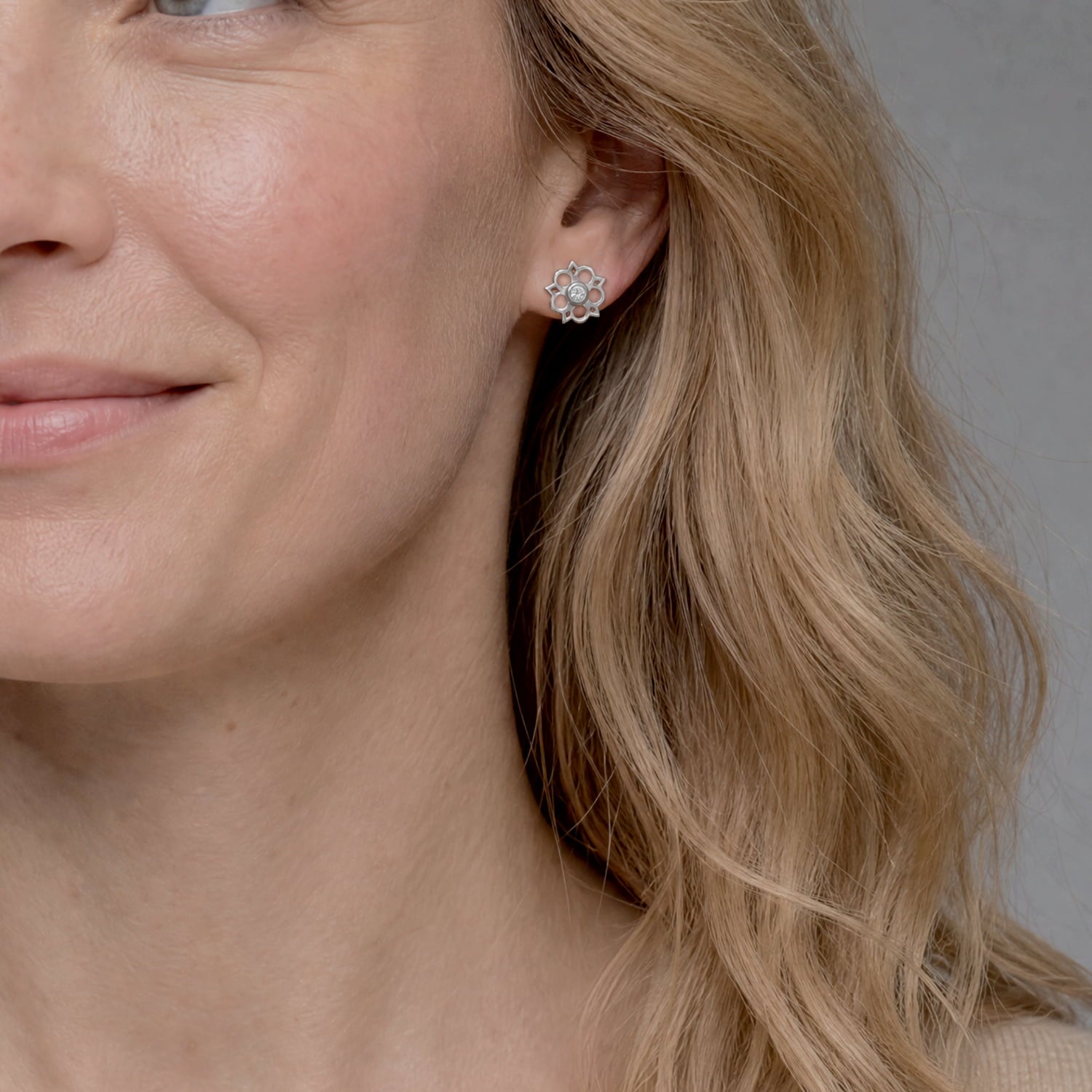 Model wears delicate sterling silver stud earrings featuring an openwork Yorkshire rose motif with a central lab-grown diamond, combining elegant floral design with contemporary silver jewellery.
