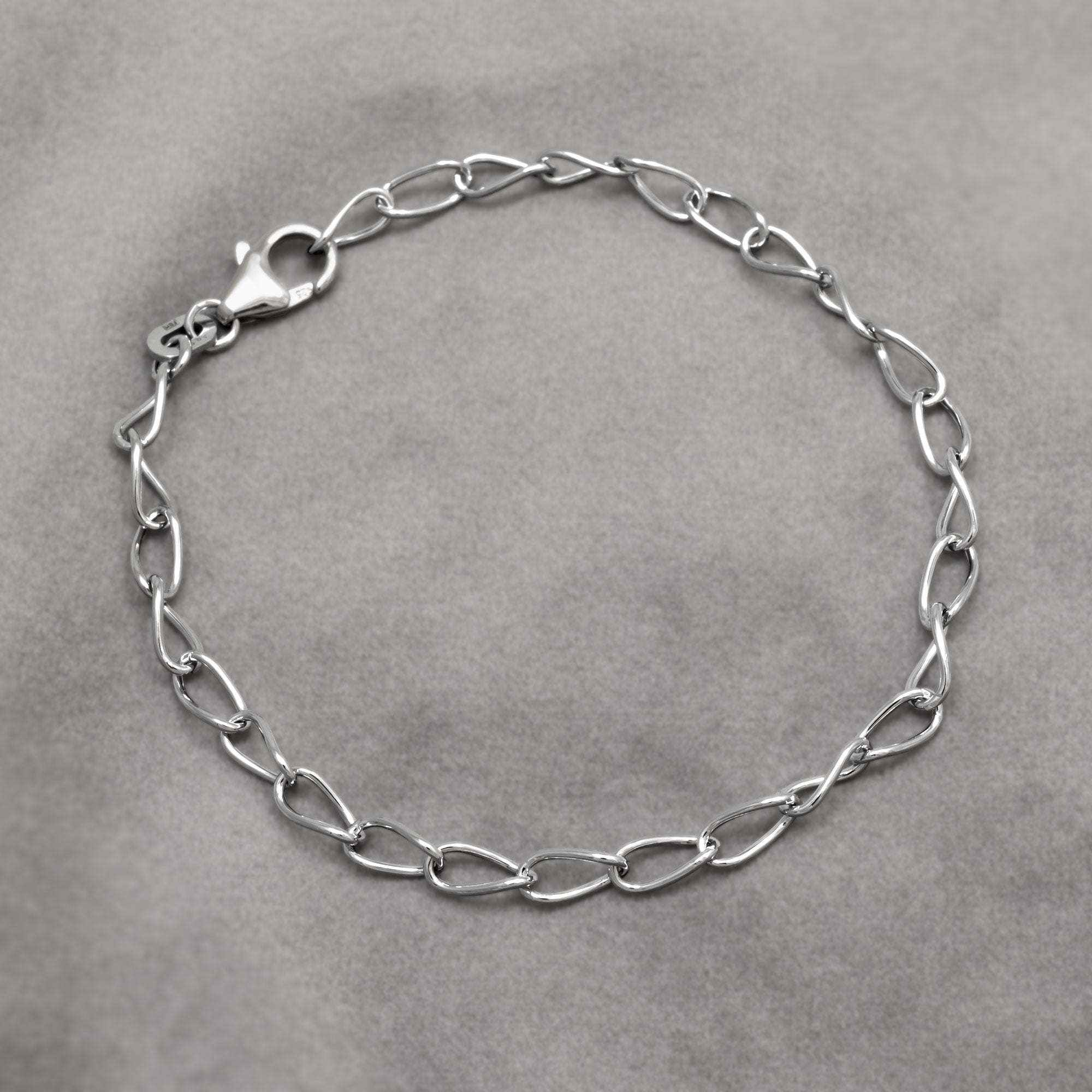 Silver twisting links chain bracelet on a grey background
