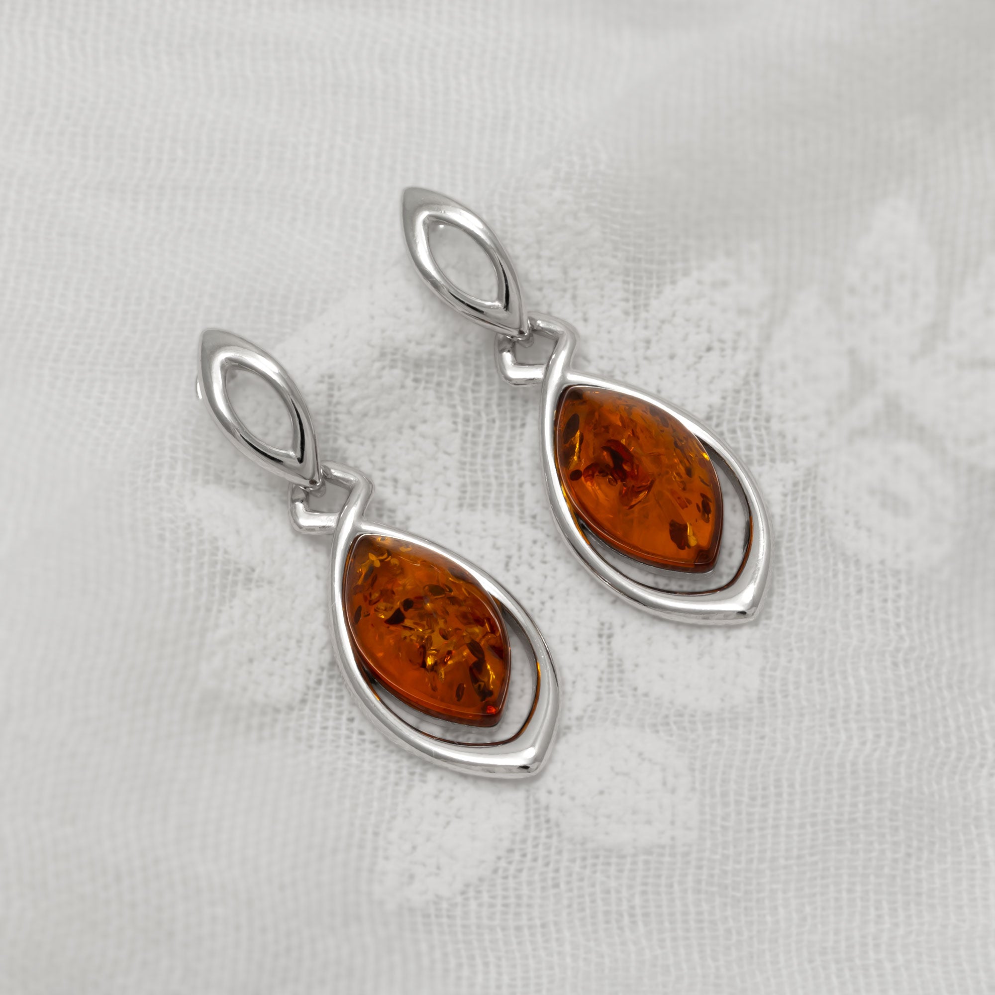 Pair of silver earrings with amber stones on a light gray background