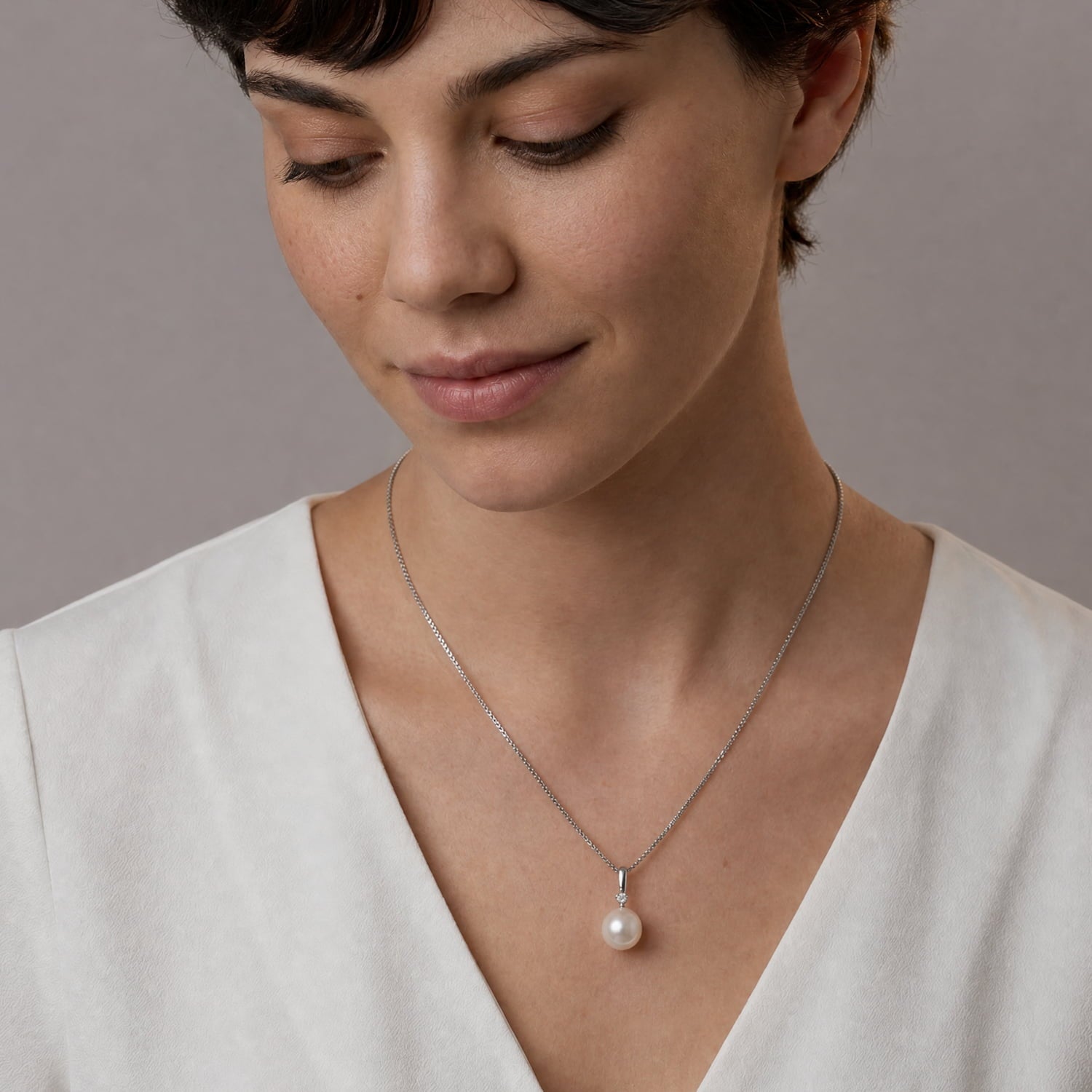 Pearl & sterling silver pendant with cubic zirconia modelled with a white blouse.