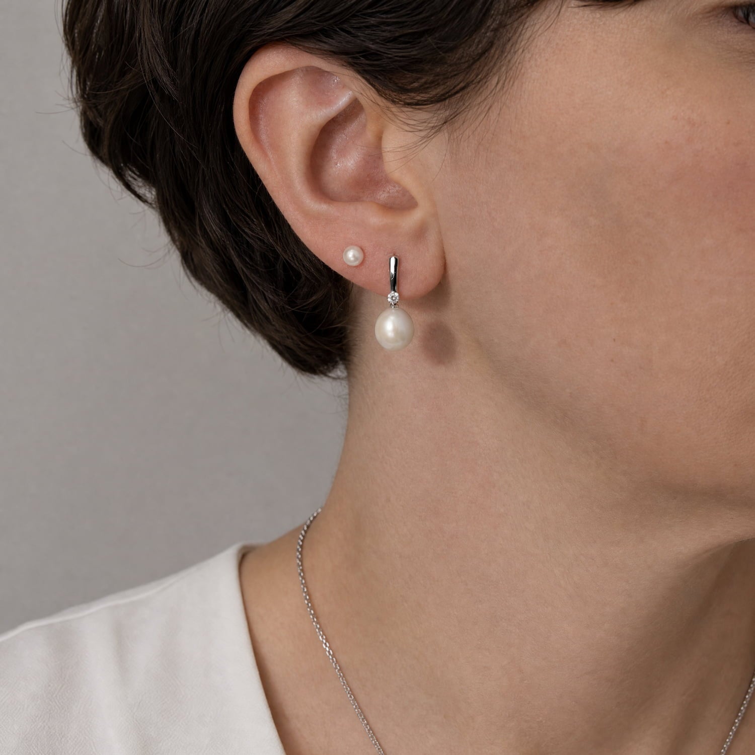 Pair of sterling silver earrings featuring large teardrop-shaped freshwater pearls accented with sparkling cubic zirconia stones for an elegant and refined look.