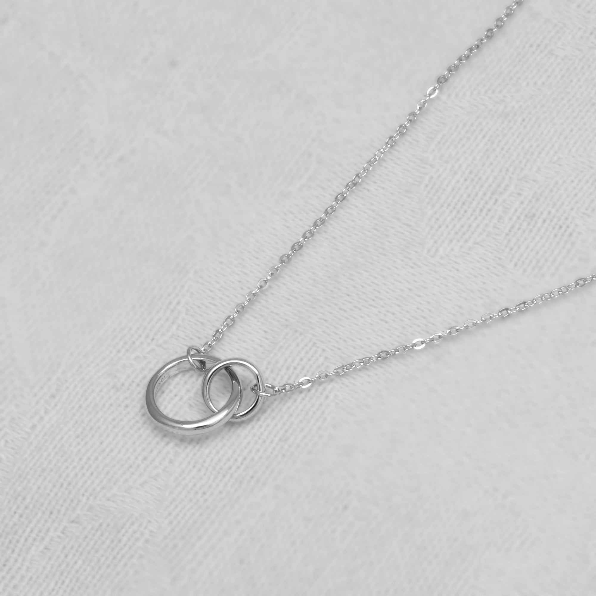 Silver necklace with interlocking rings on a white background