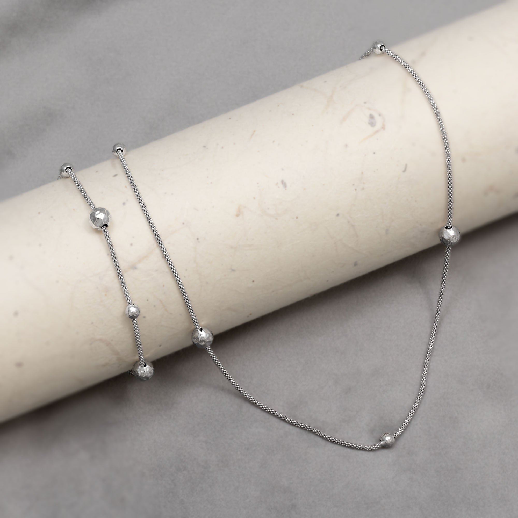 Sterling silver popcorn chain necklace and matching bracelet with textured beads on a grey background