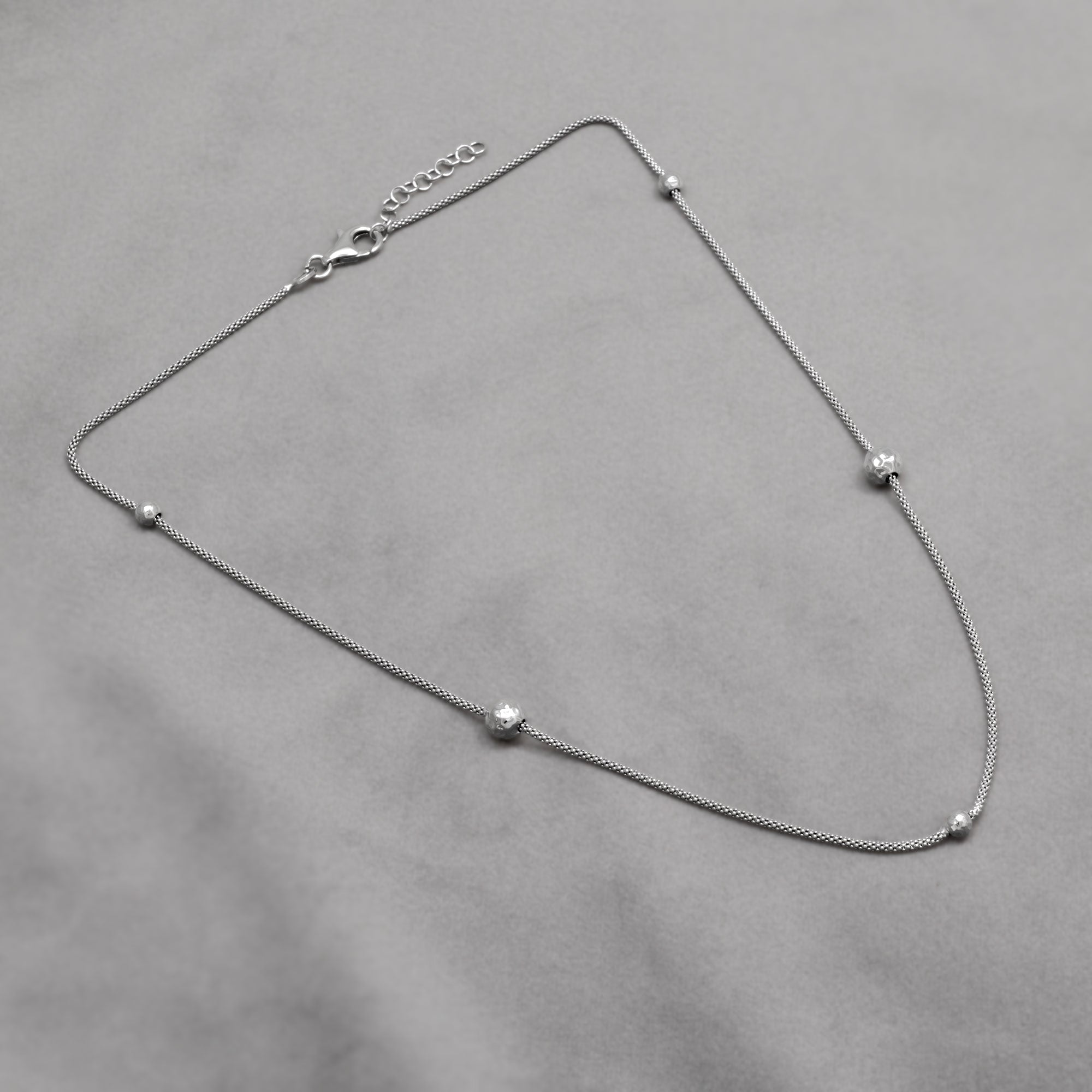 Sterling silver popcorn chain necklace with textured beads on a grey background
