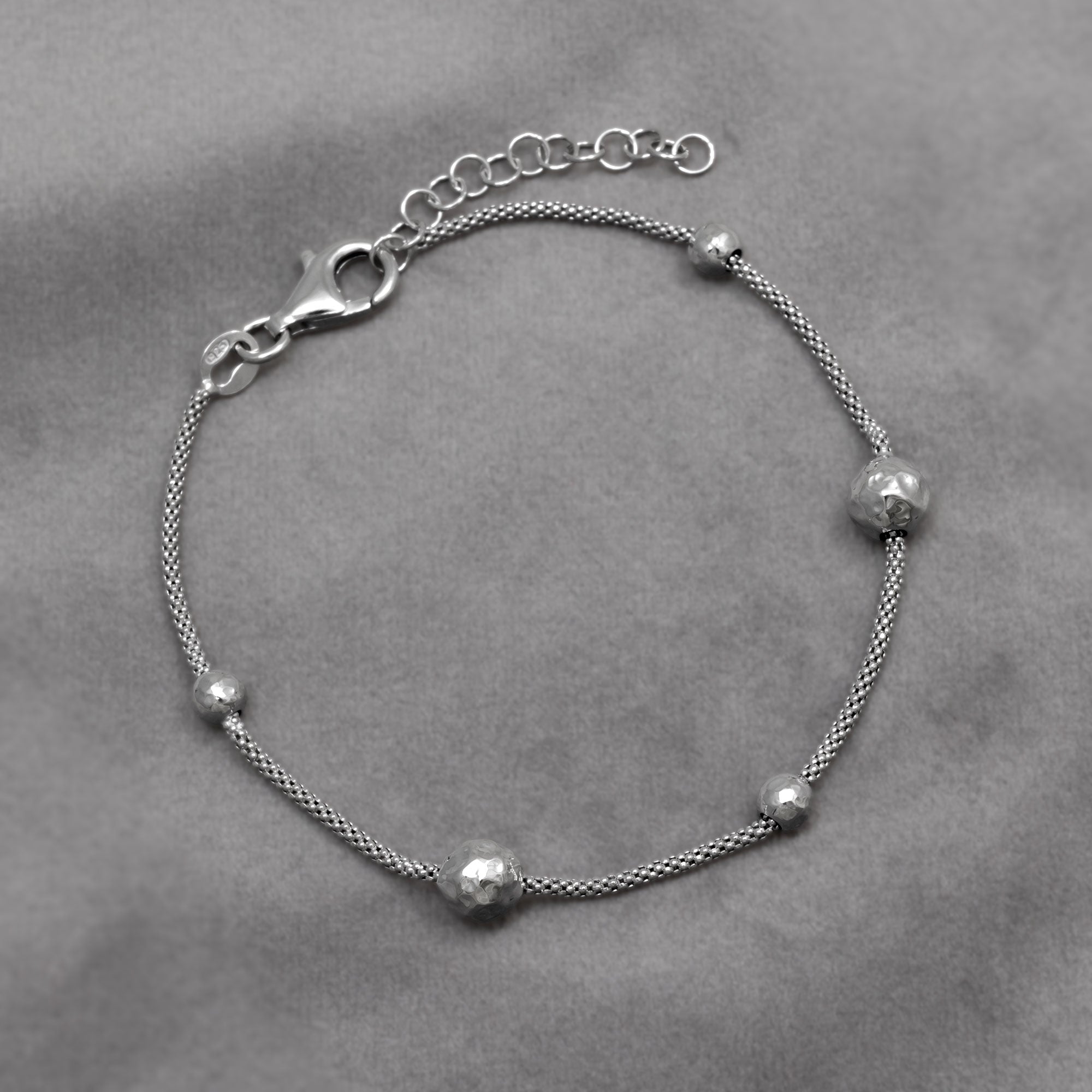 Sterling silver popcorn chain bracelet with textured beads on a grey background