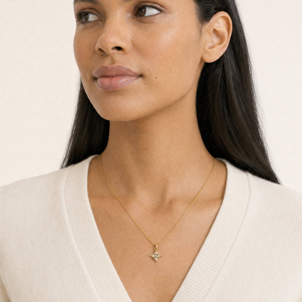 A close-up of a woman wearing a gold vermeil star-shaped pendant necklace with five lab grown diamonds, suspended from a gold box chain.