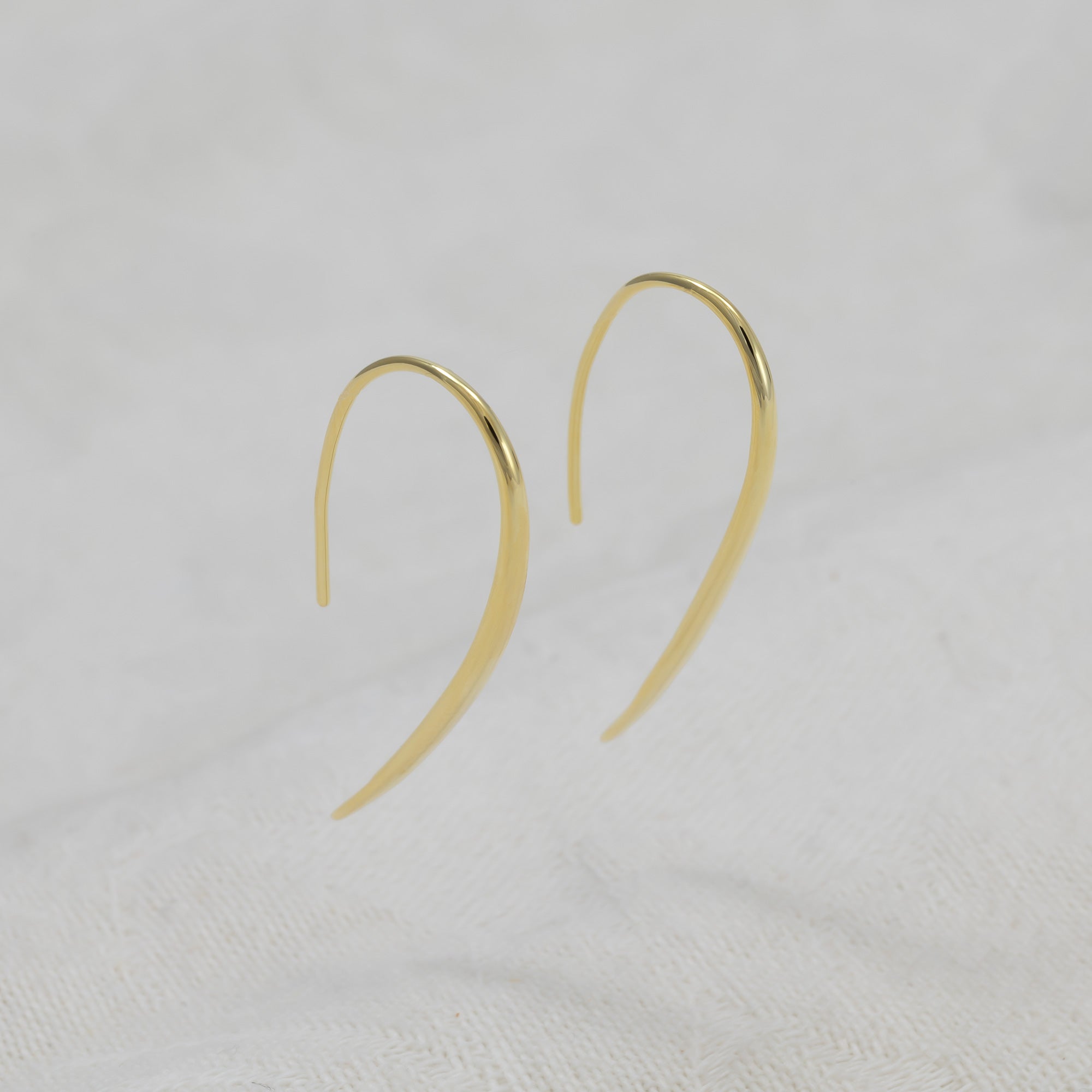 A pair of gold vermeil hook earrings with a polished finish.