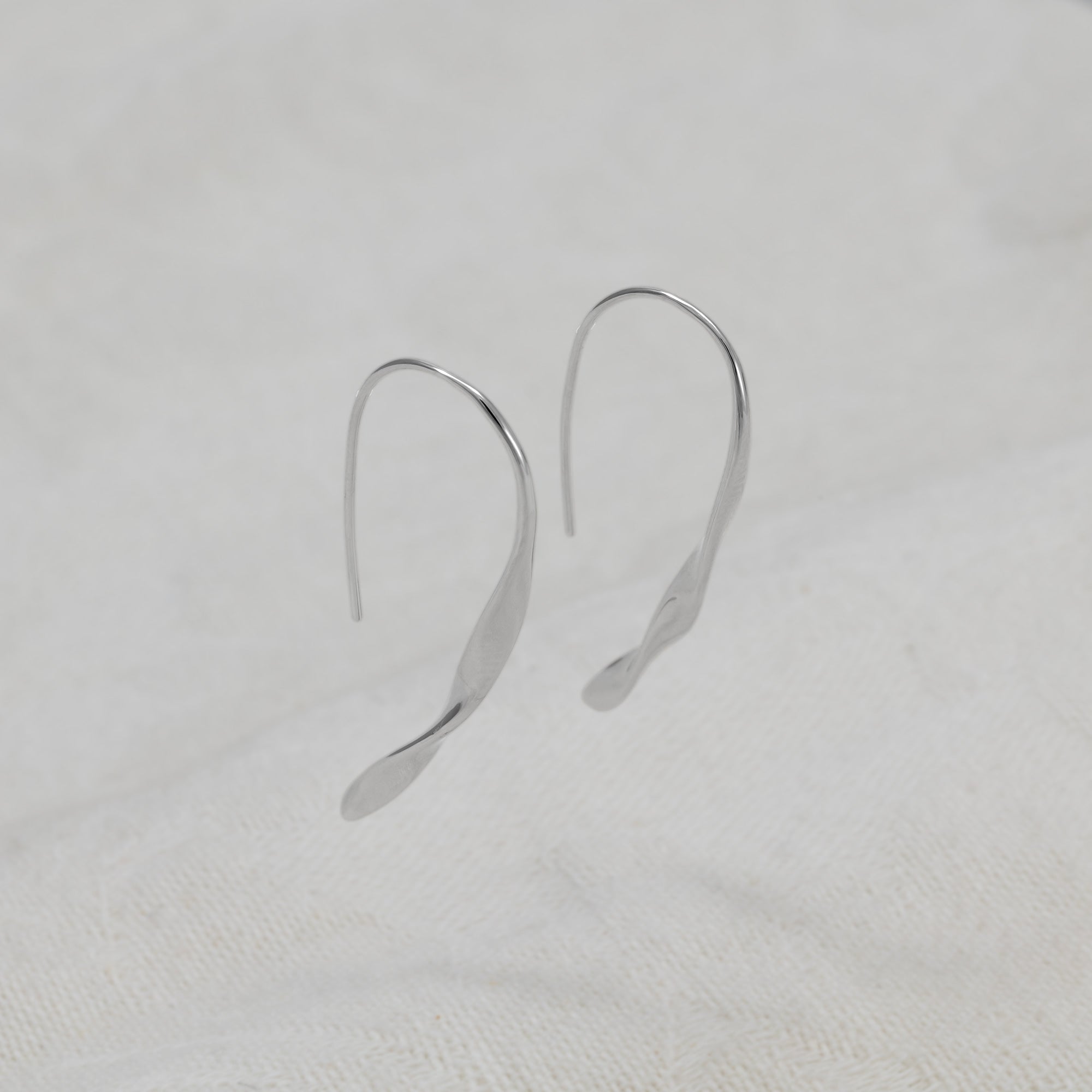 A pair of sterling silver twisting drop earrings with fishhook backs.