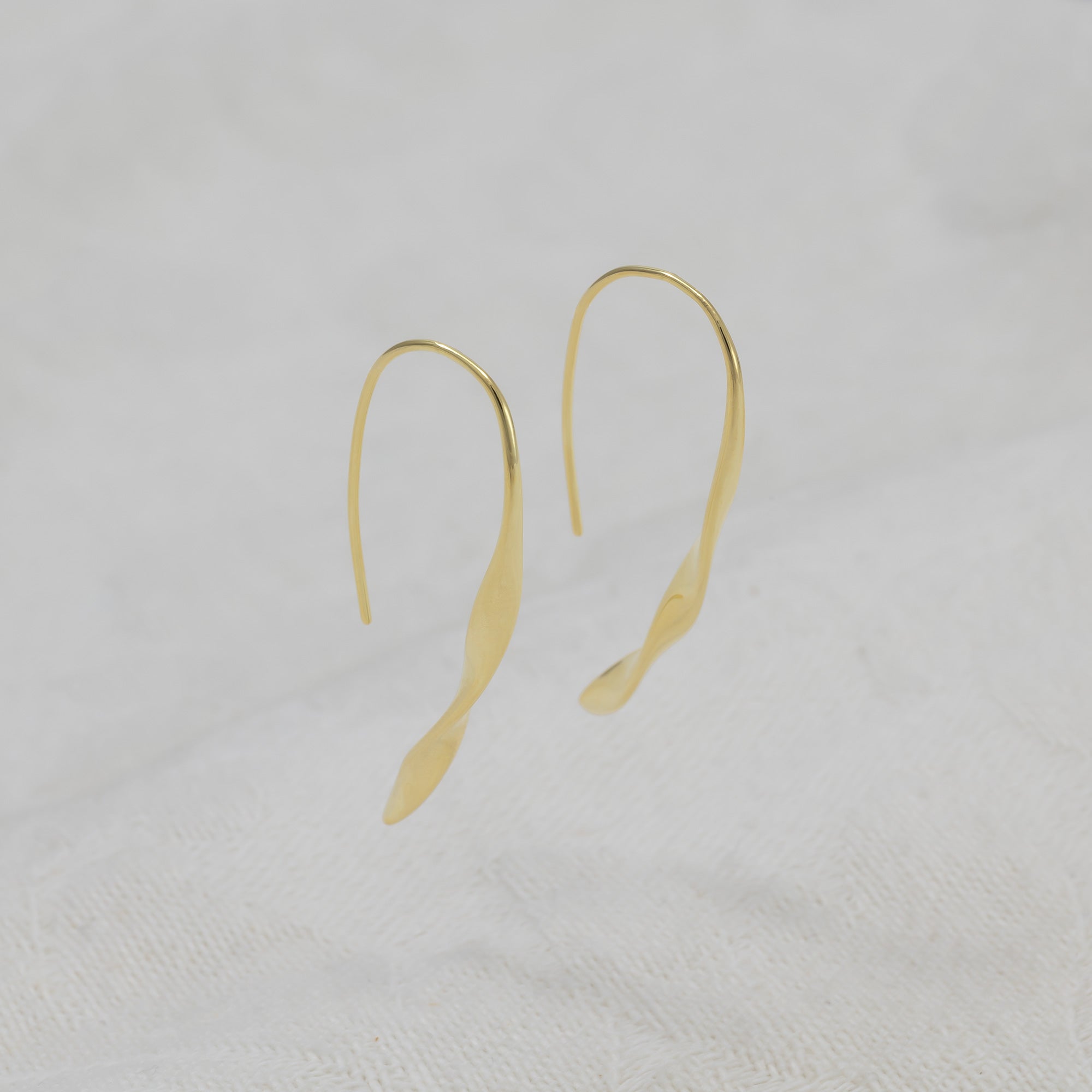 A pair of gold vermeil drop earrings with a twisted, tapered design.