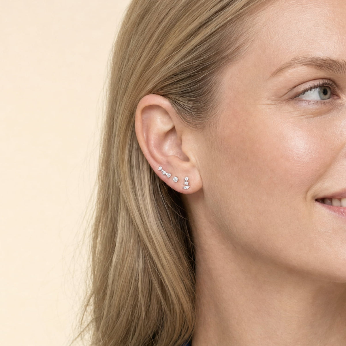 Close-up of an ear adorned with delicate silver cubic zirconia studs in curved and geometric shapes, showcasing refined sterling silver jewellery with a modern sculptural aesthetic.