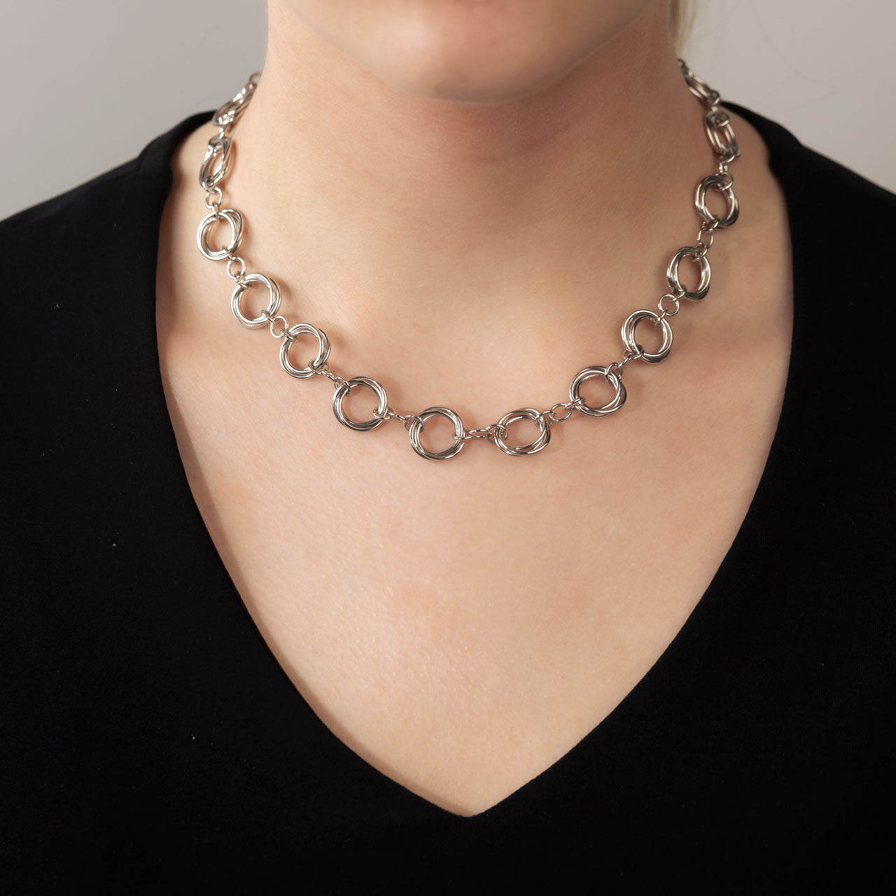 Sterling silver necklace featuring a series of interlinked circular loops with a continuous love knot design, showcasing a sculptural and contemporary style by Azendi.