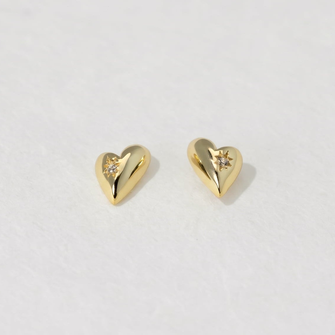 Gold heart-shaped earrings on a white background