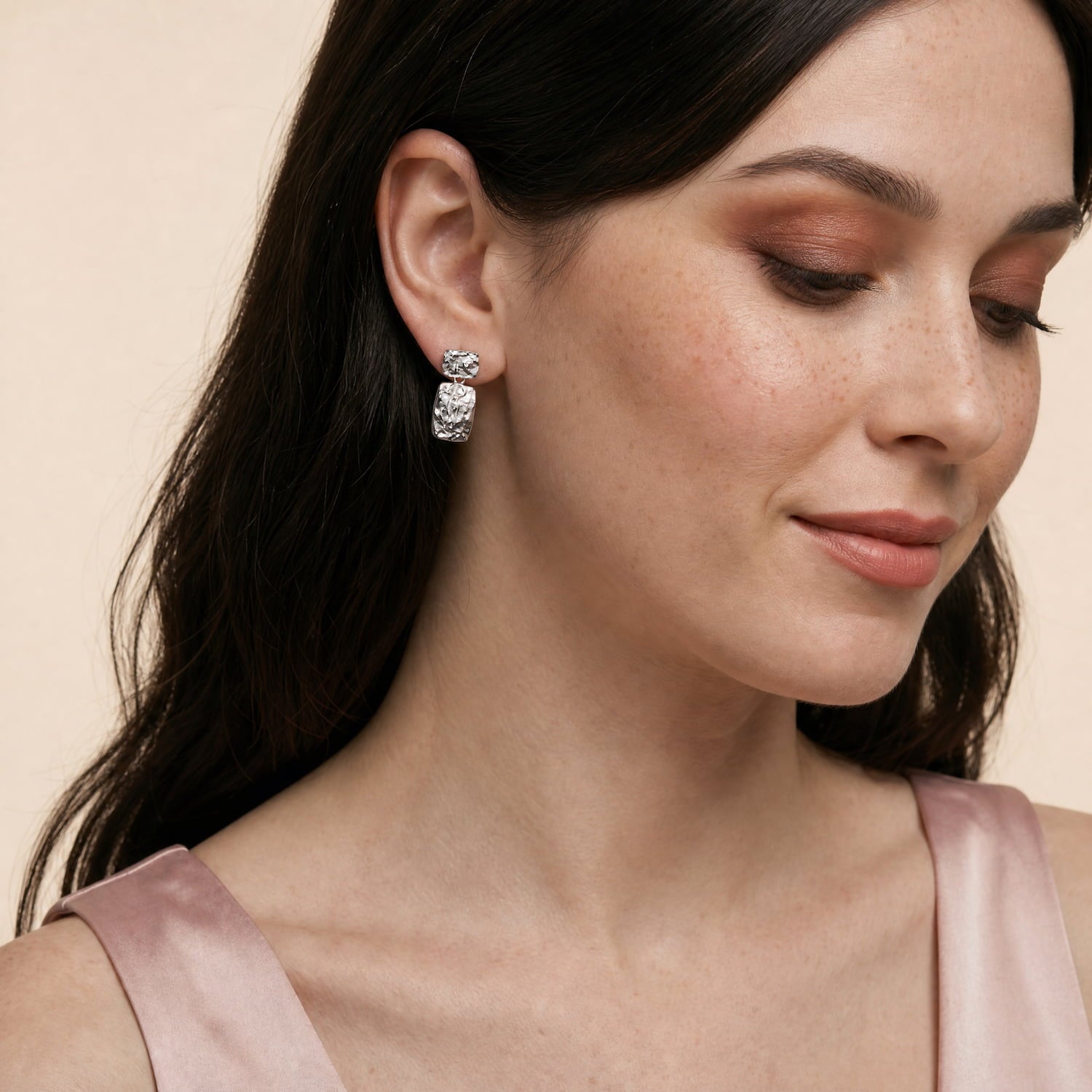 A model wears rectangular drop earrings in polished sterling silver featuring an organic, textured surface with a modern sculptural design for refined British silver jewellery.