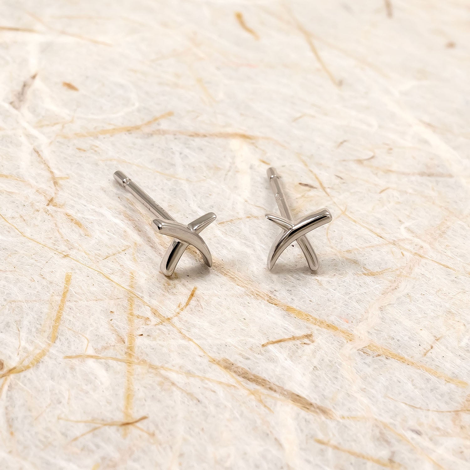 Pair of polished sterling silver stud earrings featuring a contemporary crossed design, embodying refined simplicity and modern elegance in British silver jewellery.