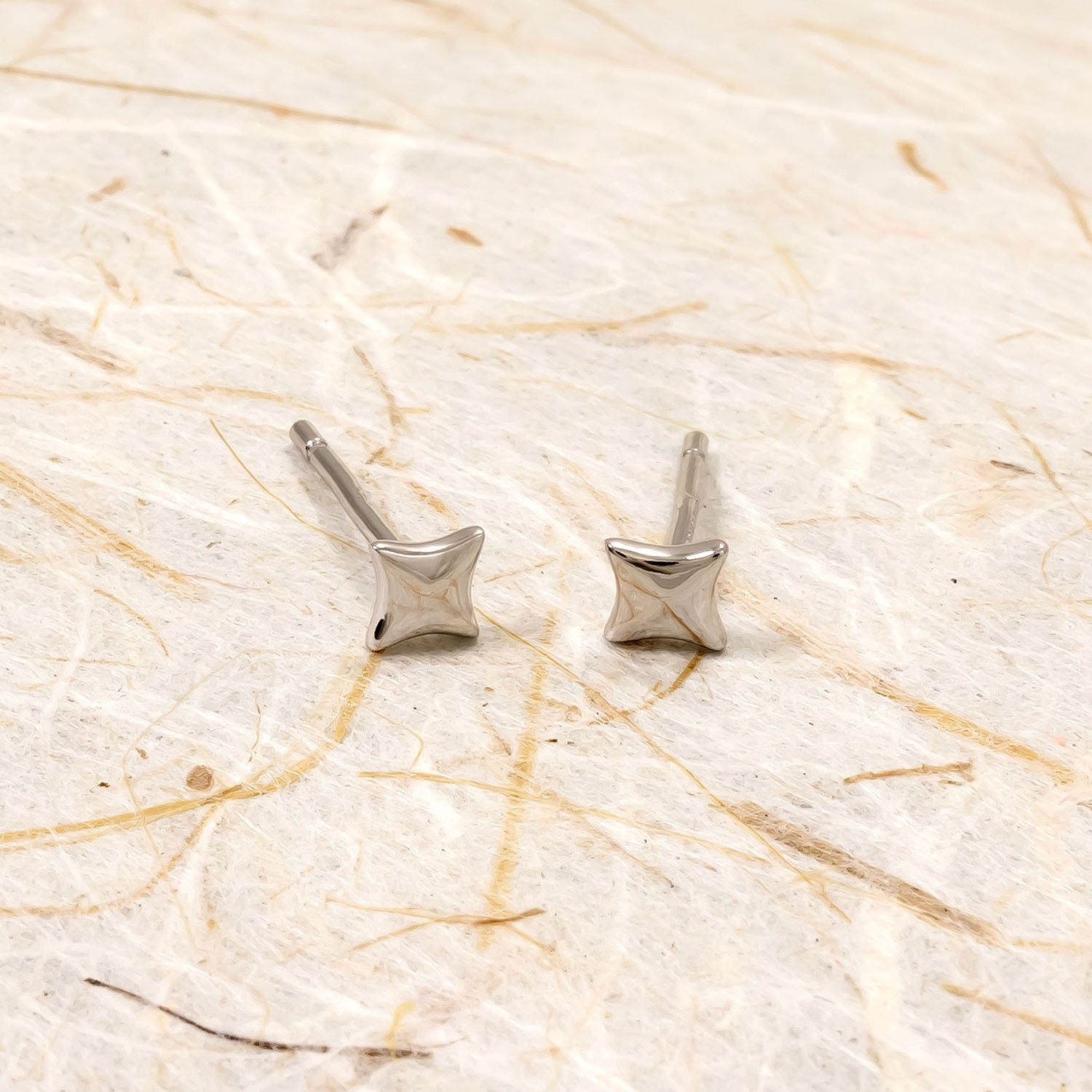 Pair of polished sterling silver stud earrings shaped as sculptural four-point stars, showcasing a sleek and modern design in fine silver jewellery by Azendi.