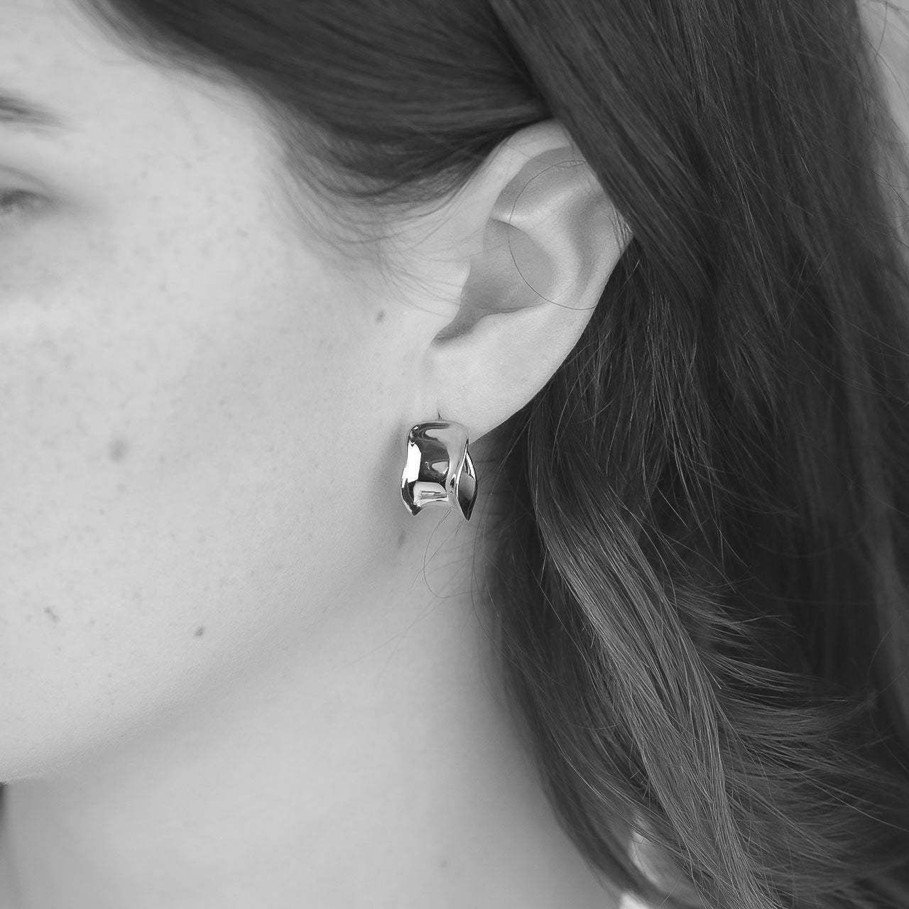 Sterling silver hoop earrings featuring a distinctive beveled and wavy design, offering a sculptural and contemporary silhouette in fine silver jewellery.