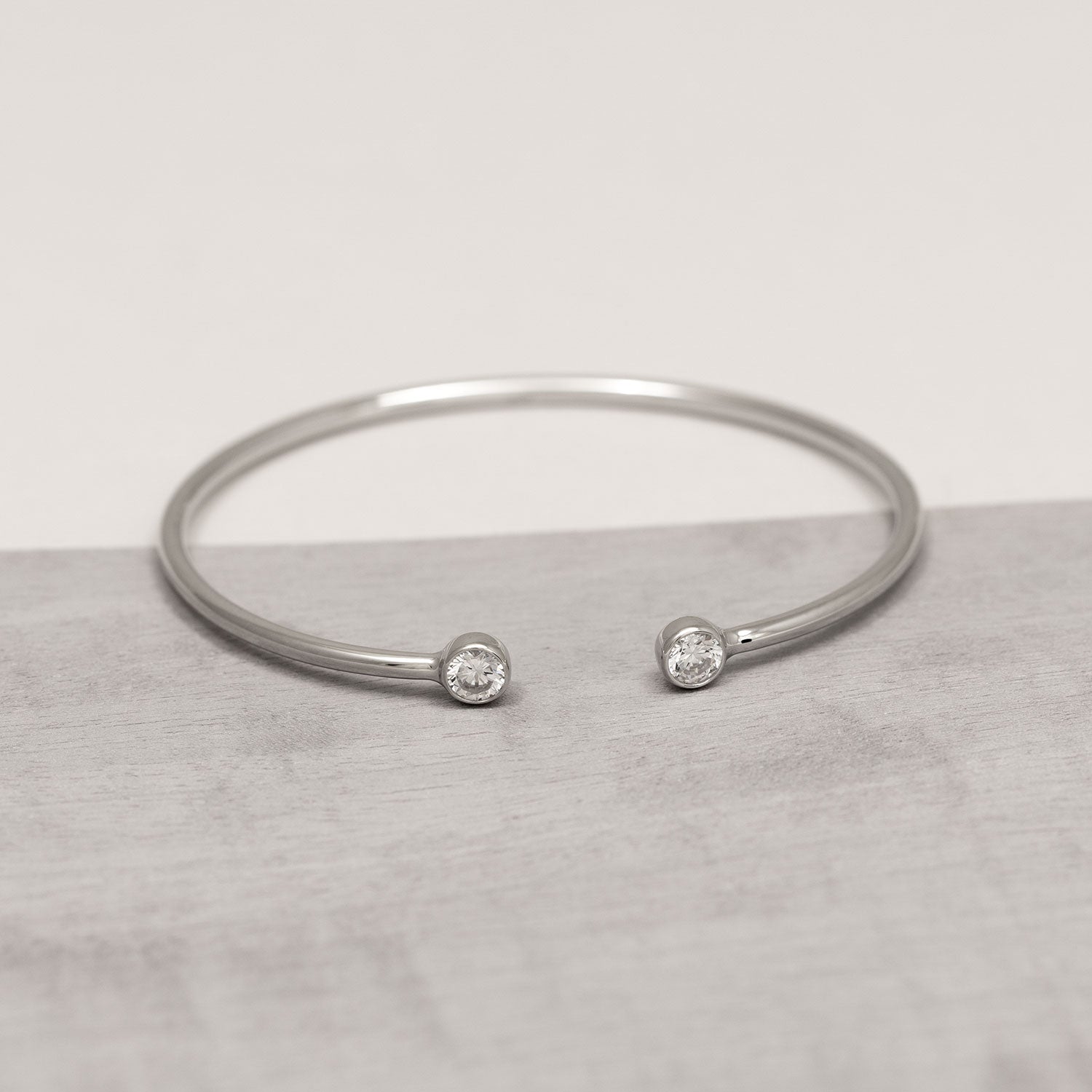 Elegant sterling silver cuff bangle featuring open ends set with sparkling cubic zirconia stones, showcasing a sleek, flexible design in contemporary silver jewellery.