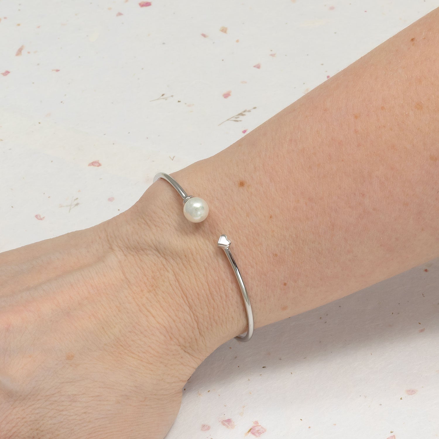 Open sterling silver flexi cuff featuring a polished heart detail opposite a lustrous shell pearl, embodying contemporary elegance in designer silver jewellery.