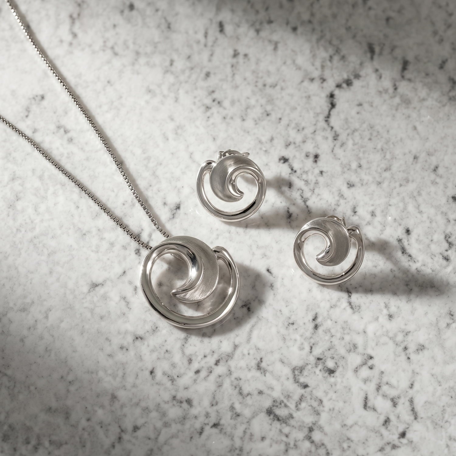 Pair of sterling silver curling stud earrings with a satin and polished finish, featuring a fluid, sculptural design inspired by natural forms for refined contemporary elegance.