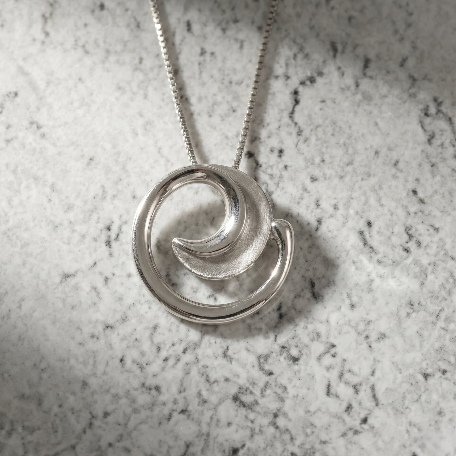 Sterling silver pendant featuring a graceful curling design with contrasting satin and polished finishes, suspended from a delicate chain for modern, elegant silver jewellery.