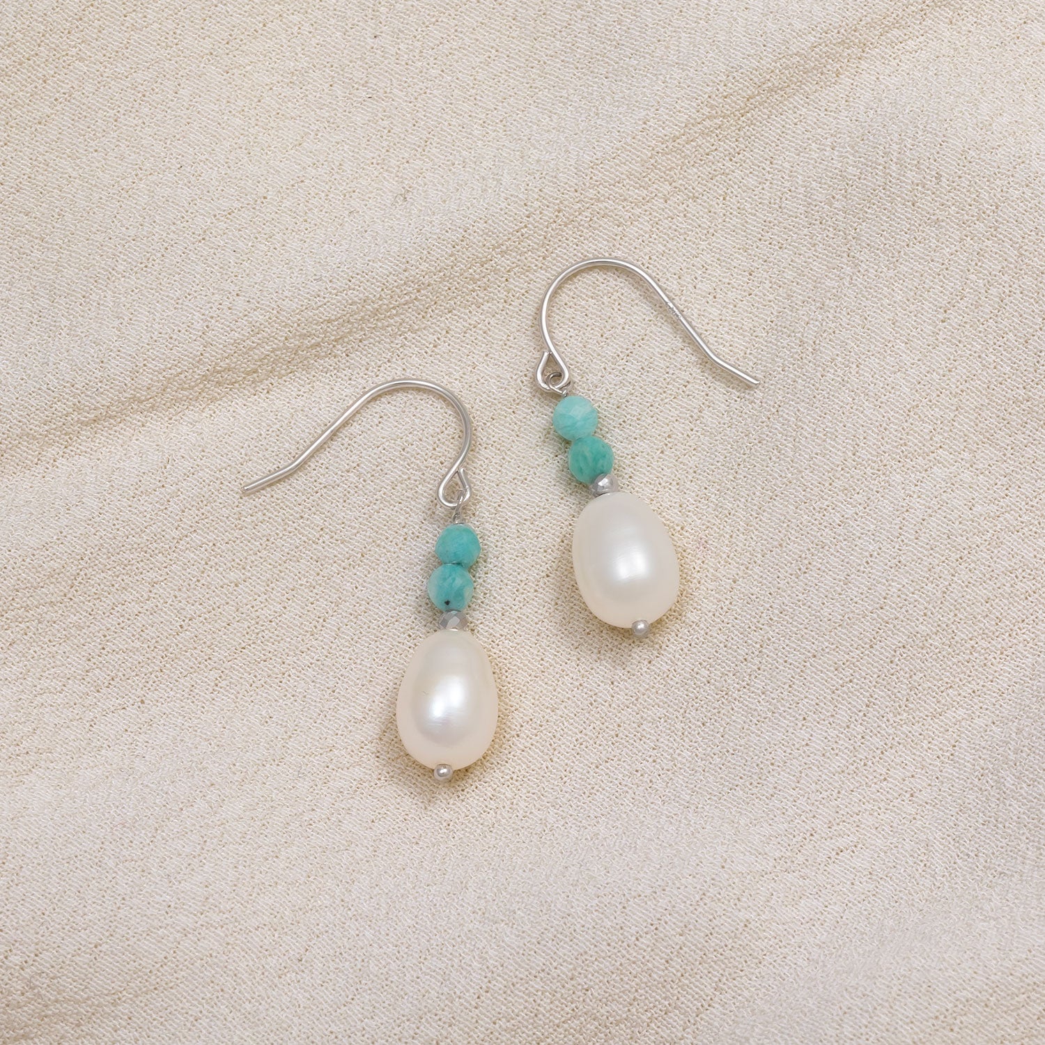 Sterling silver drop earrings featuring smooth freshwater pearls accented by small amazonite beads, combining natural elegance with contemporary design.