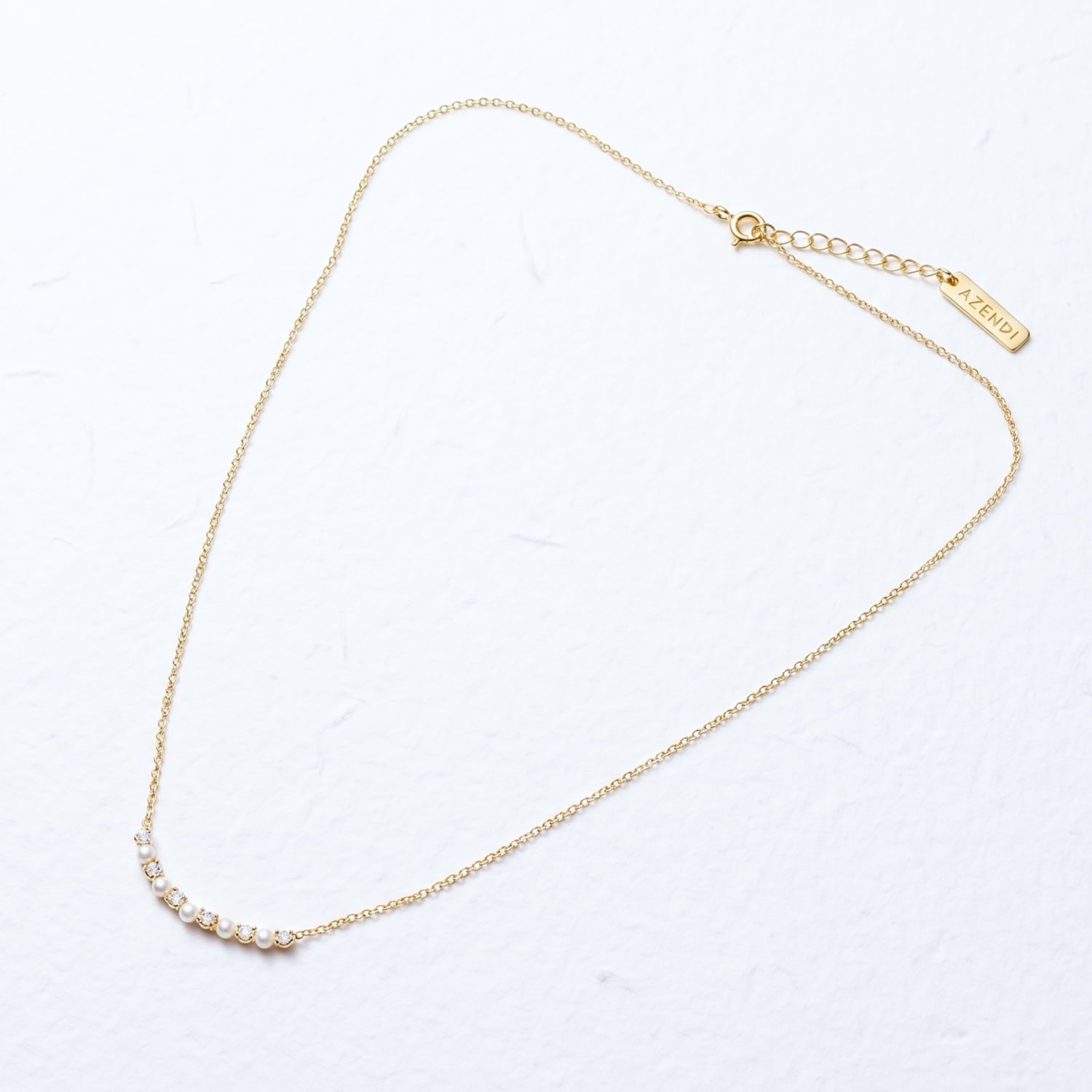 Adjustable gold vermeil necklace with a gently curved bar featuring alternating freshwater pearls and cubic zirconia stones, crafted for a delicate and refined statement.