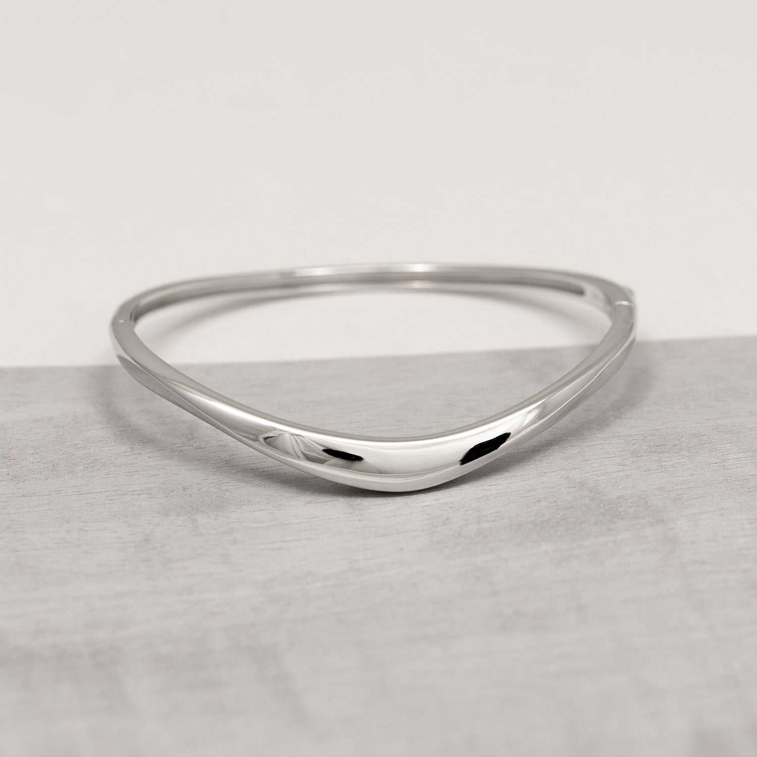 Sleek sterling silver hinged bangle featuring a slim, sculptural wave design with a polished finish for a refined and contemporary look.