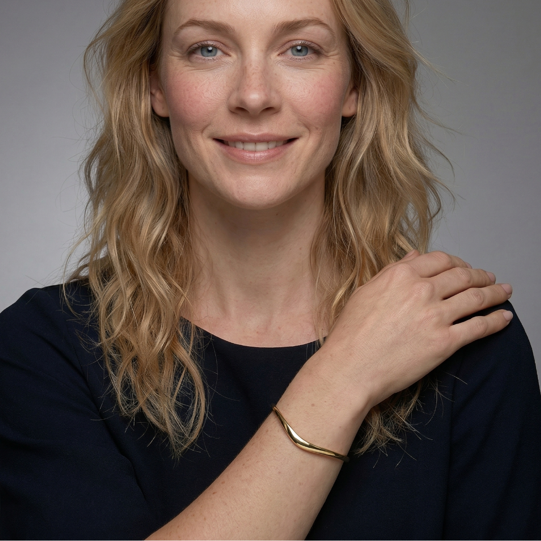 Elegant gold vermeil bangle with a slender wave design, gracefully curved around the wrist for a minimalist and sculptural look in contemporary jewellery.