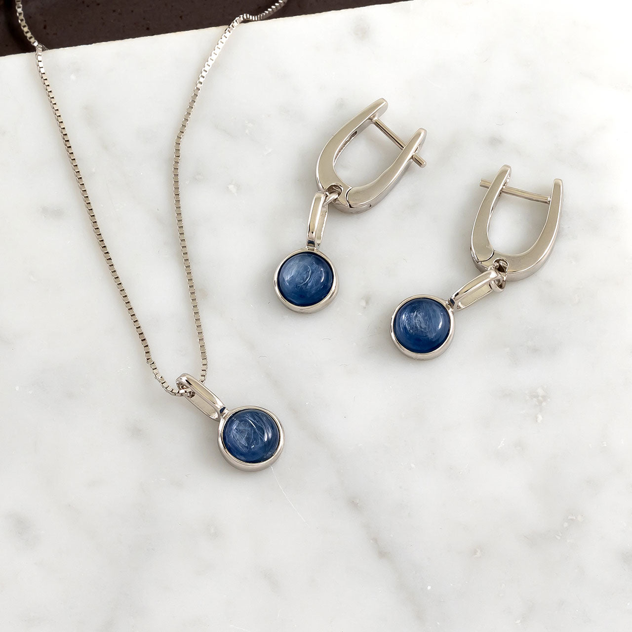 Sterling silver drop earrings featuring round kyanite stones set in smooth bezel mounts, paired with a matching pendant necklace on a fine box chain for elegant wear.