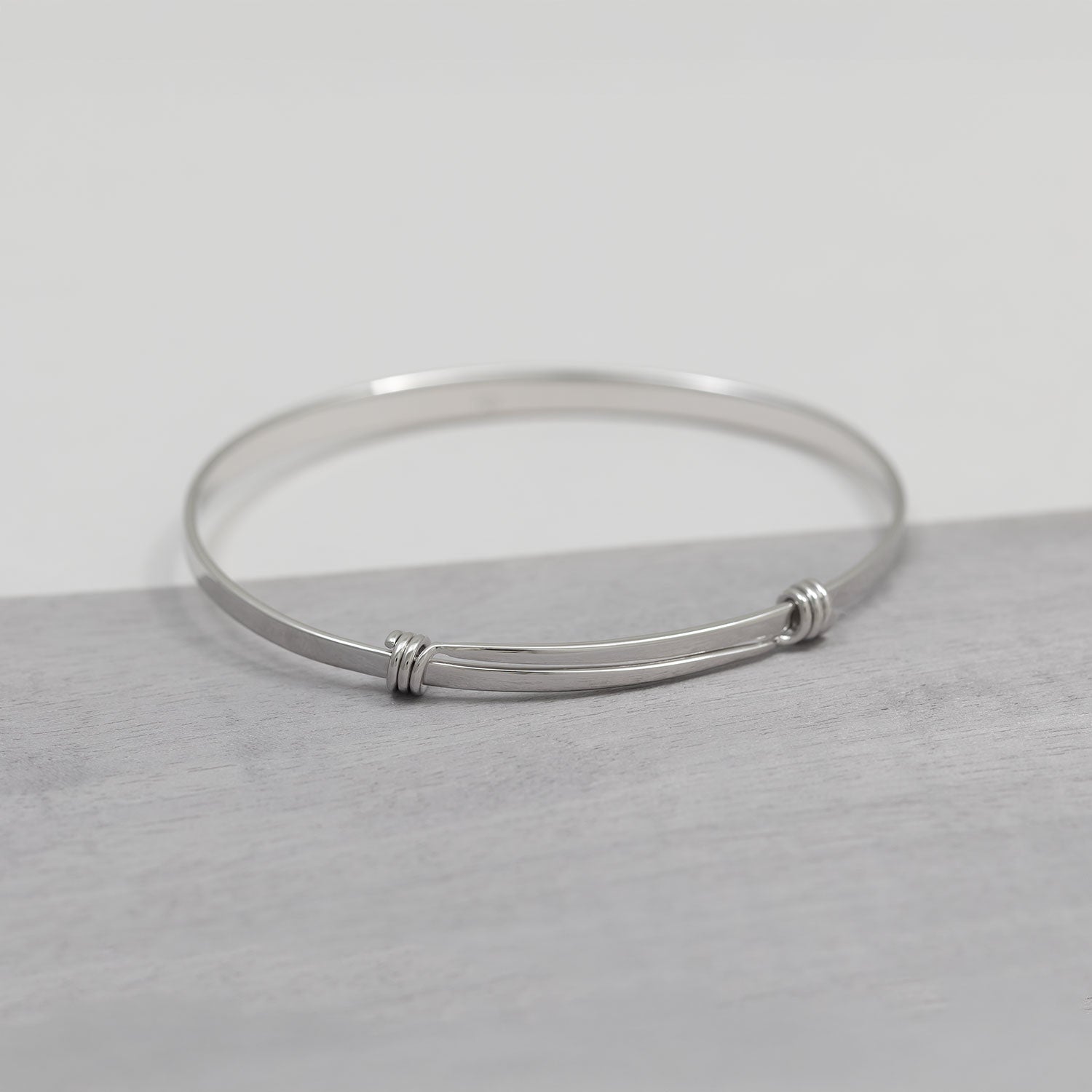 Sleek sterling silver expandable bangle featuring a minimalist curved bar design with subtle wire detailing, embodying refined contemporary silver jewellery.