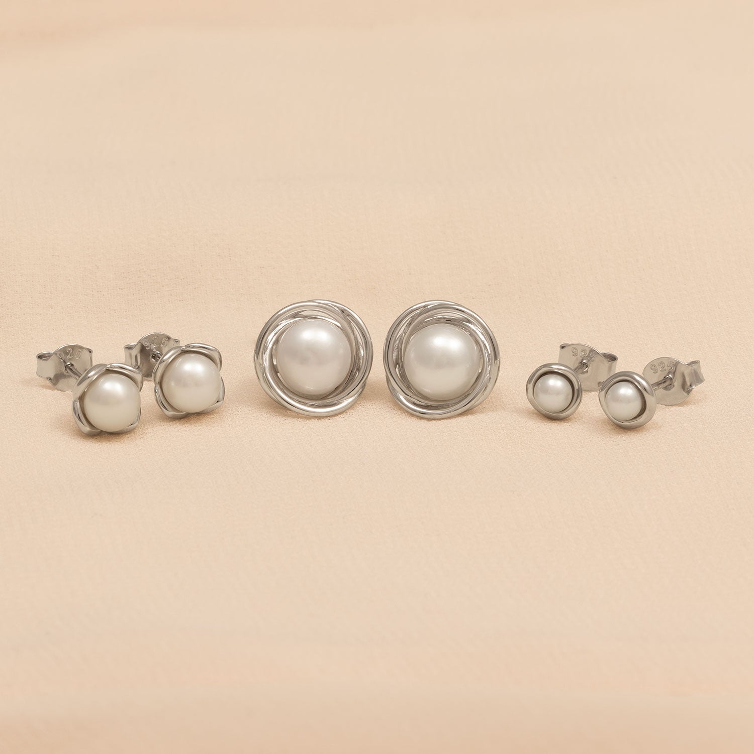 Pair of sterling silver stud earrings featuring luminous freshwater pearls set within a delicate floral-inspired silver frame, blending classic elegance with modern design.