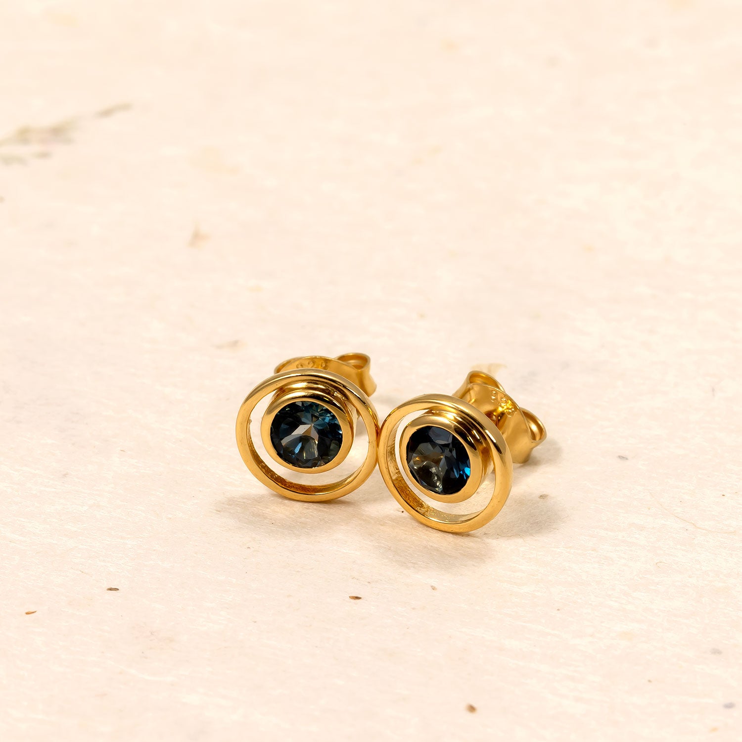 Pair of gold vermeil stud earrings featuring polished circular frames encasing deep blue London Blue Topaz gemstones for a refined and elegant look.