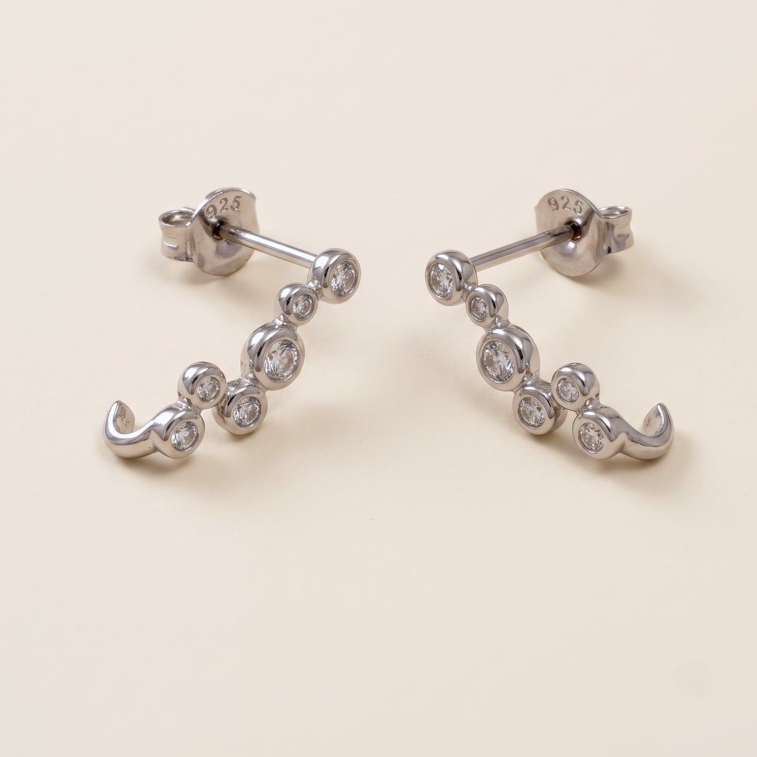 Pair of sterling silver half hoop earrings featuring a cluster of sparkling cubic zirconia stones, exemplifying expert British craftsmanship and contemporary fine jewellery design.