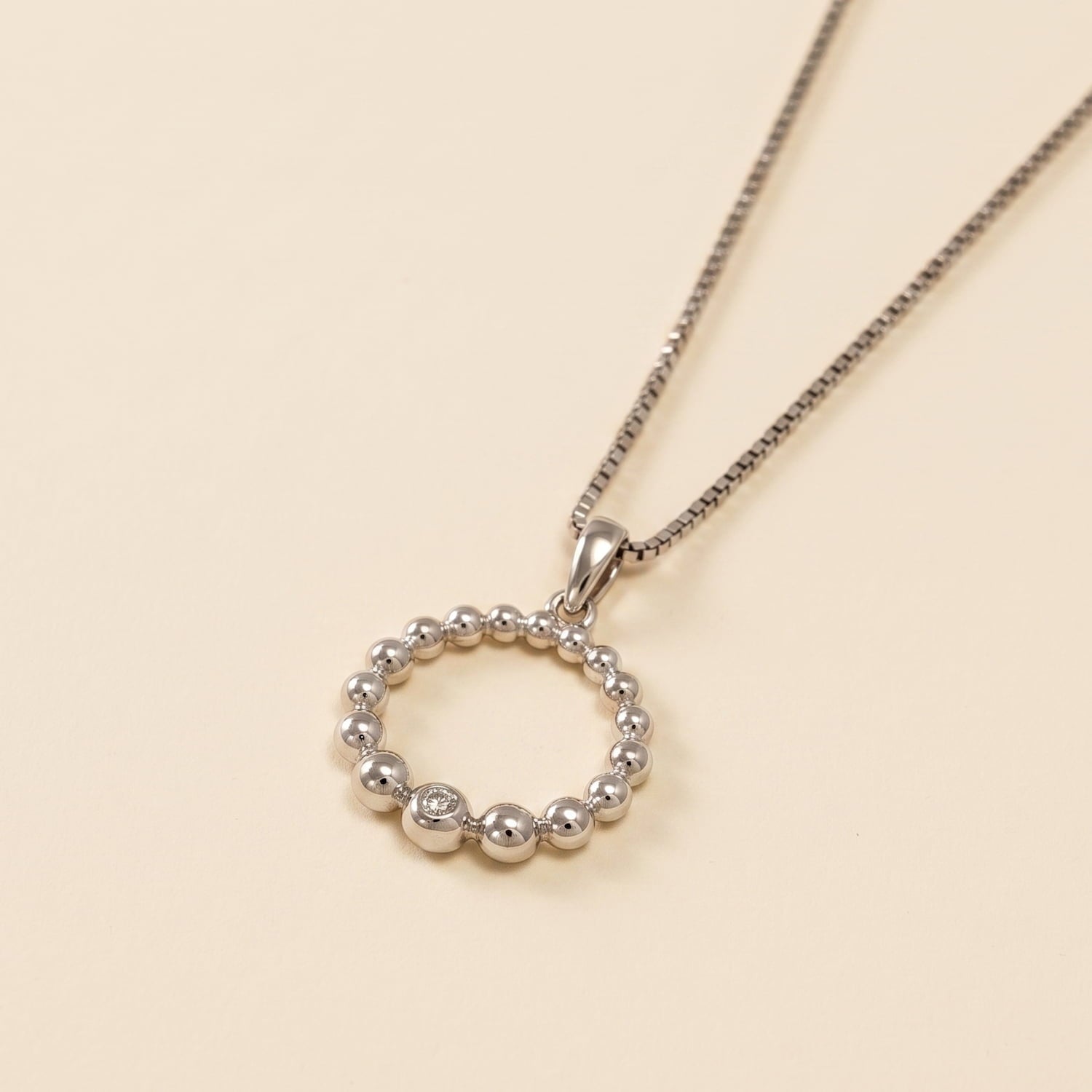 Sterling silver pendant featuring graduated beaded circle design accented with a single cubic zirconia, suspended on a fine delicate chain, showcasing expert British craftsmanship.