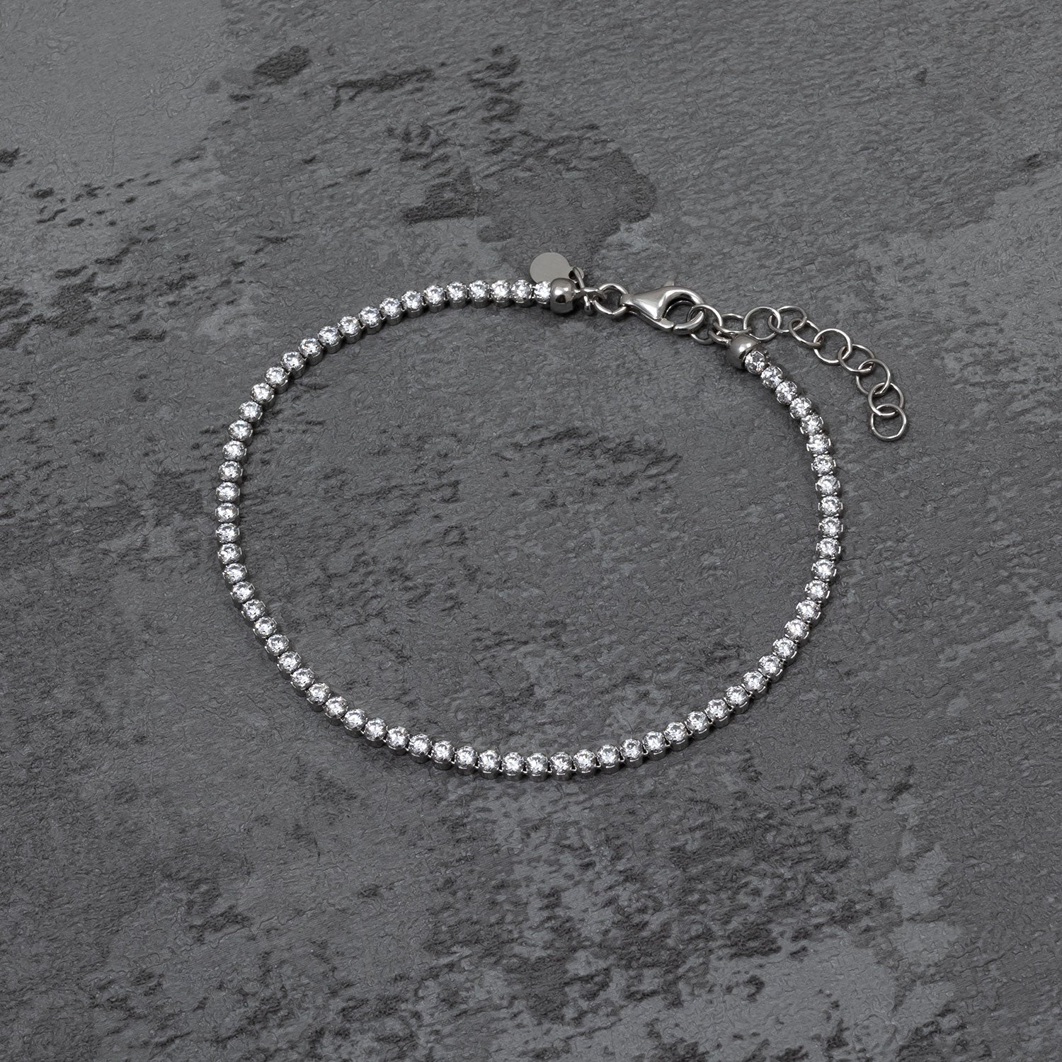 Delicate sterling silver tennis bracelet featuring a continuous row of sparkling cubic zirconia stones with an adjustable clasp for a refined, classic look.