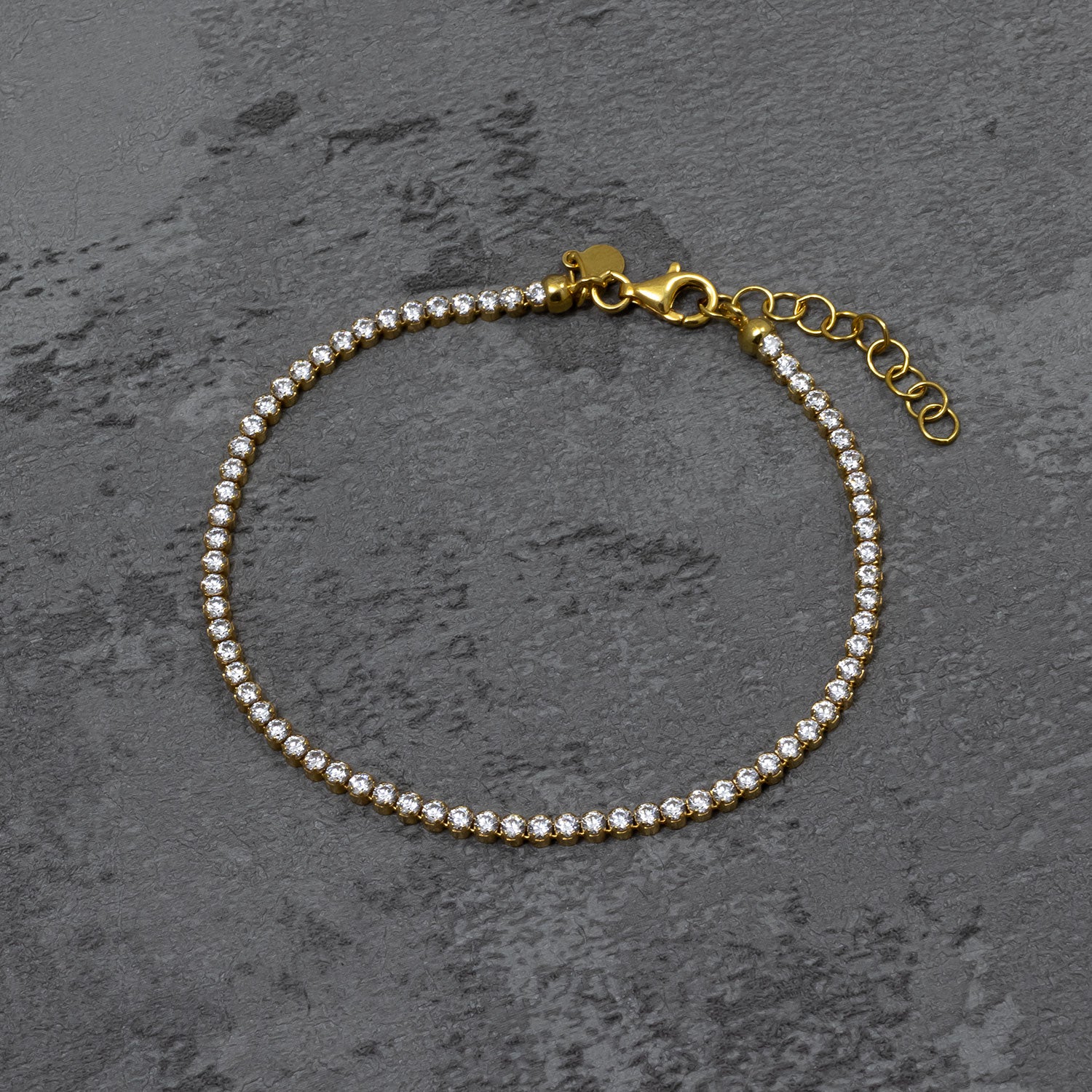 Delicate gold vermeil tennis bracelet featuring a continuous row of sparkling cubic zirconia stones with adjustable length and classic, elegant design.