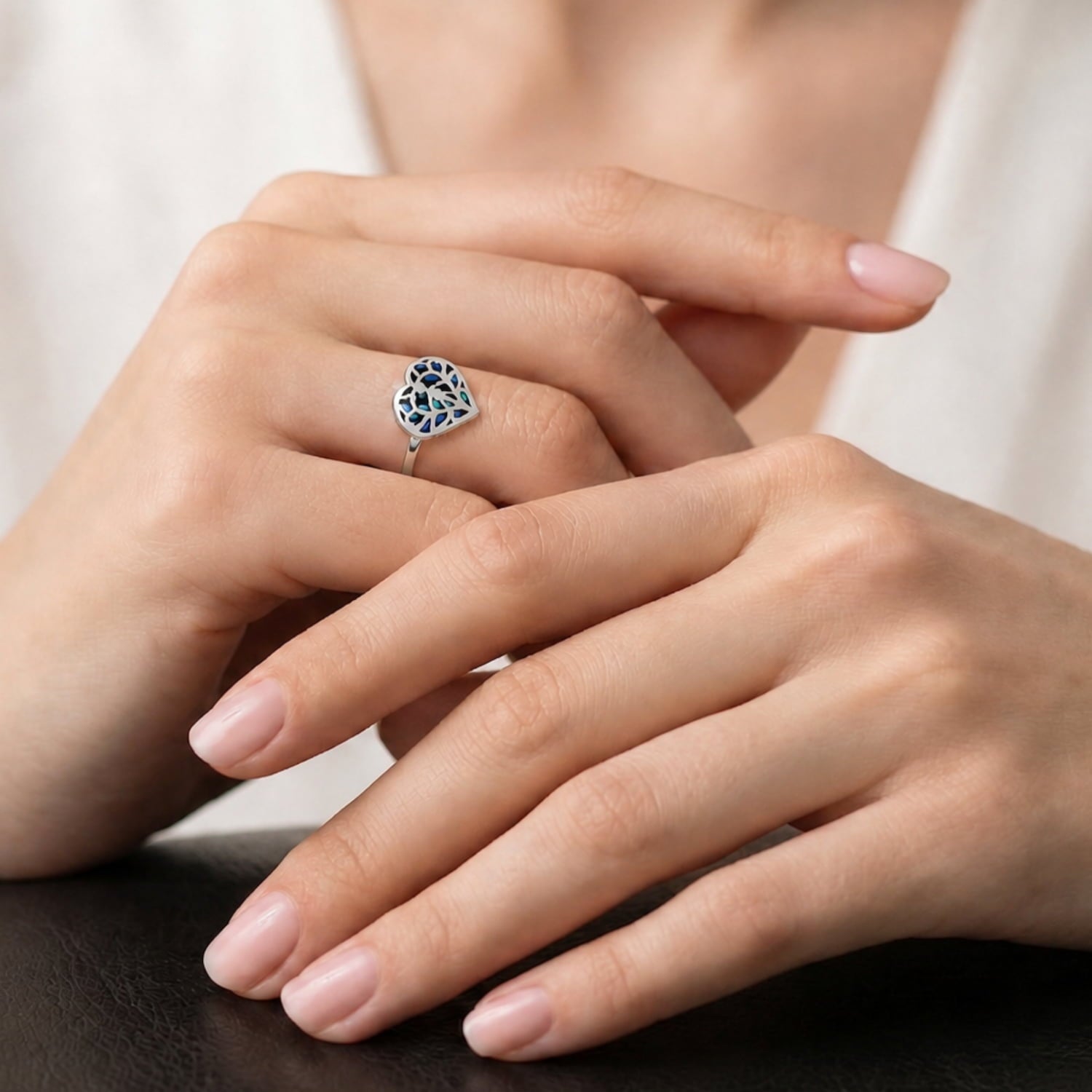 Model wears sterling silver ring featuring a sculptural openwork heart design with iridescent abalone inlay, combining contemporary craftsmanship and elegant silver jewellery style.