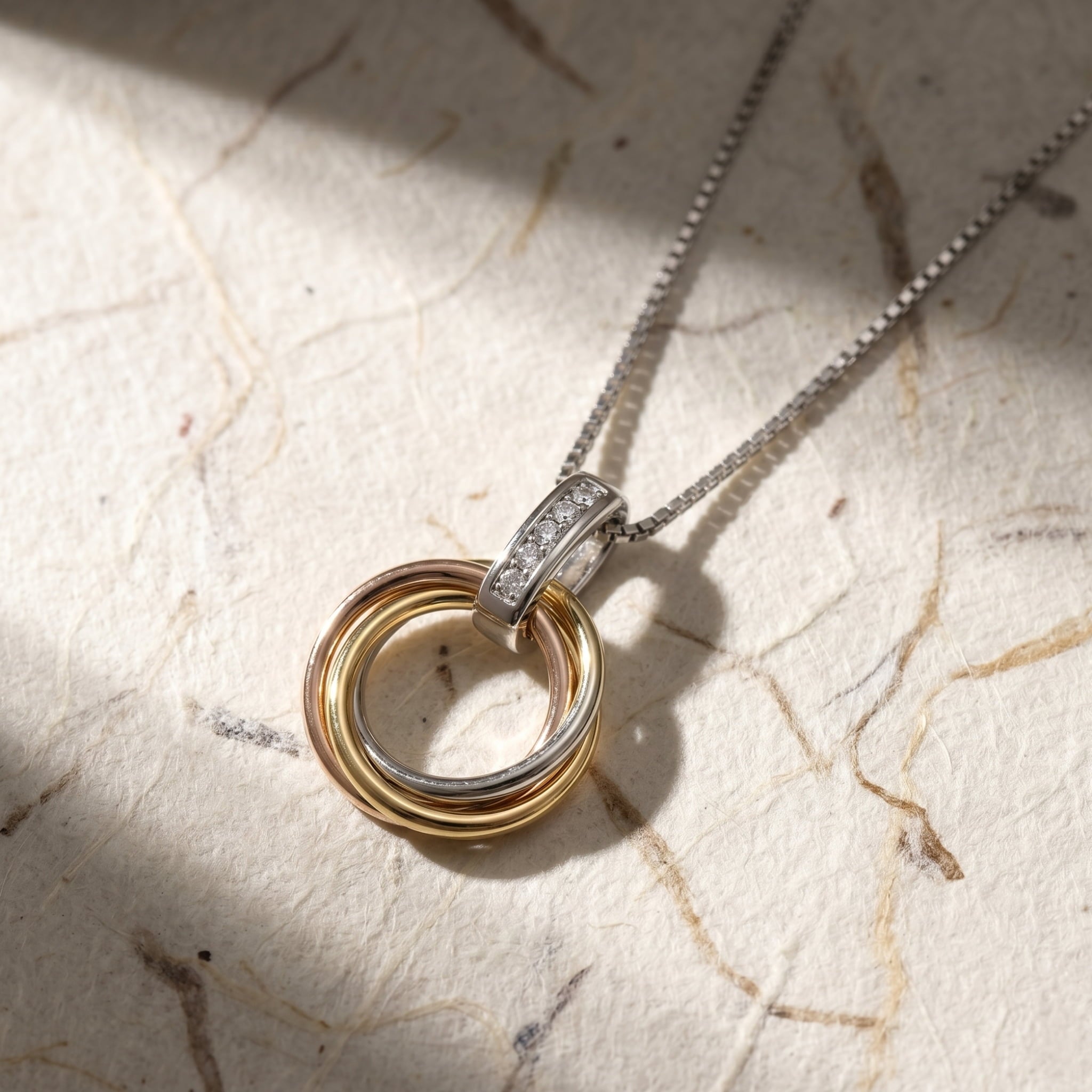 Necklace with a pendant featuring interlocking rings on a textured surface