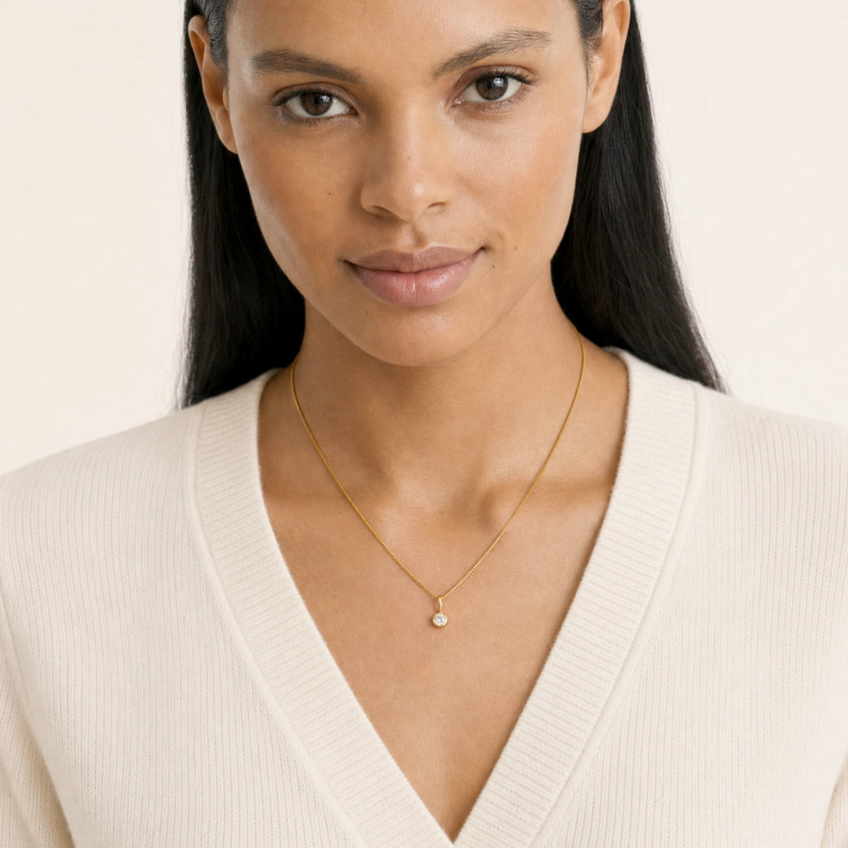 A close-up of a model wearing an elegant gold vermeil pendant necklace featuring a single 0.15 carat lab grown diamond set in a bezel, suspended from a fine chain, exemplifying modern minimalism.