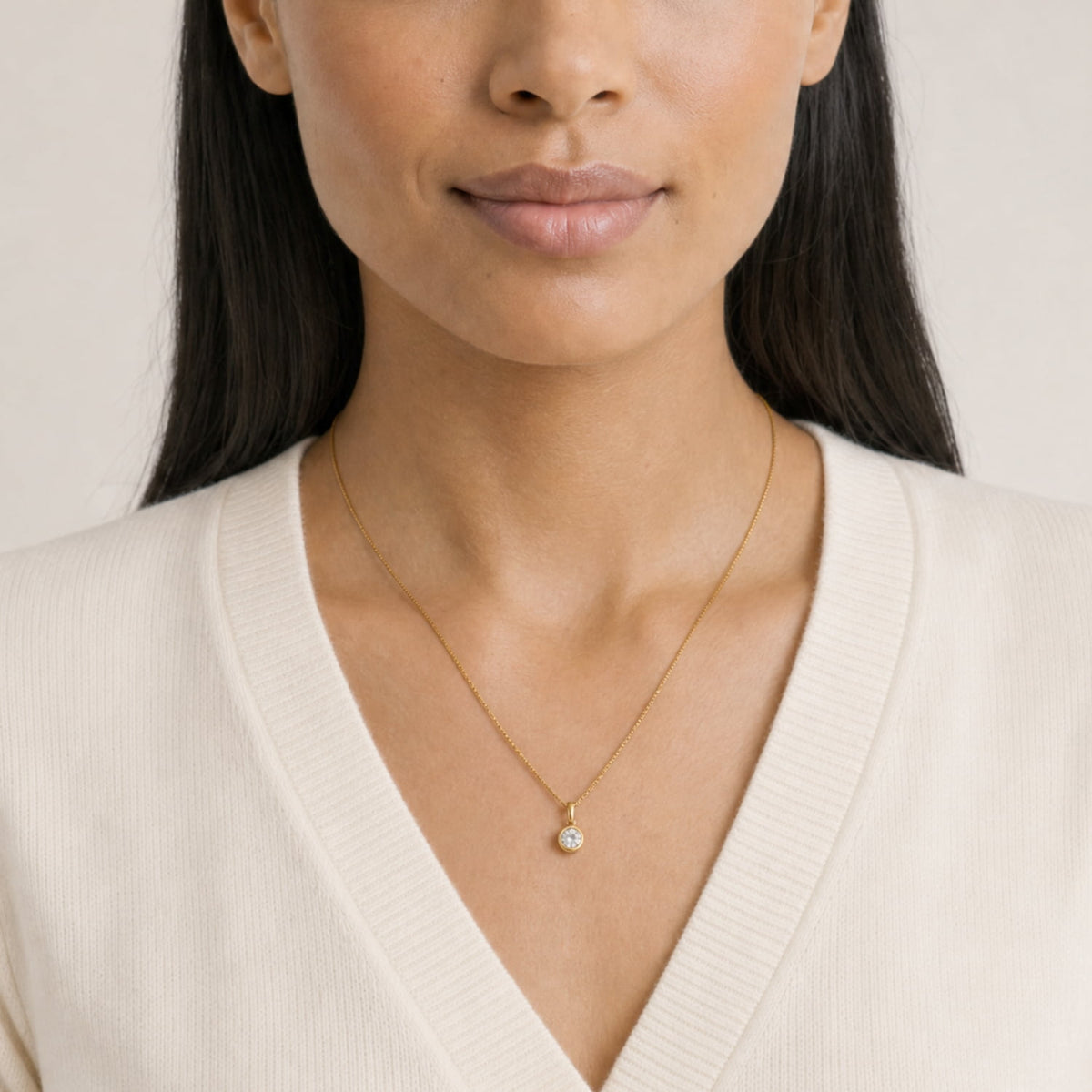Close up of model wearing an elegant gold vermeil pendant necklace featuring a single 0.25 carat lab grown diamond in a bezel setting on a fine chain, embodying refined simplicity.