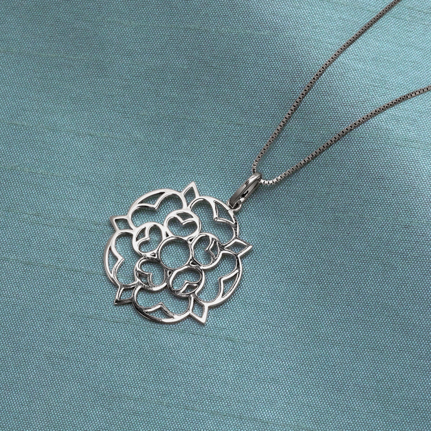 Openwork sterling silver pendant in a large Yorkshire rose design, suspended from a delicate chain, showcasing a sculptural and refined contemporary silver jewellery style.