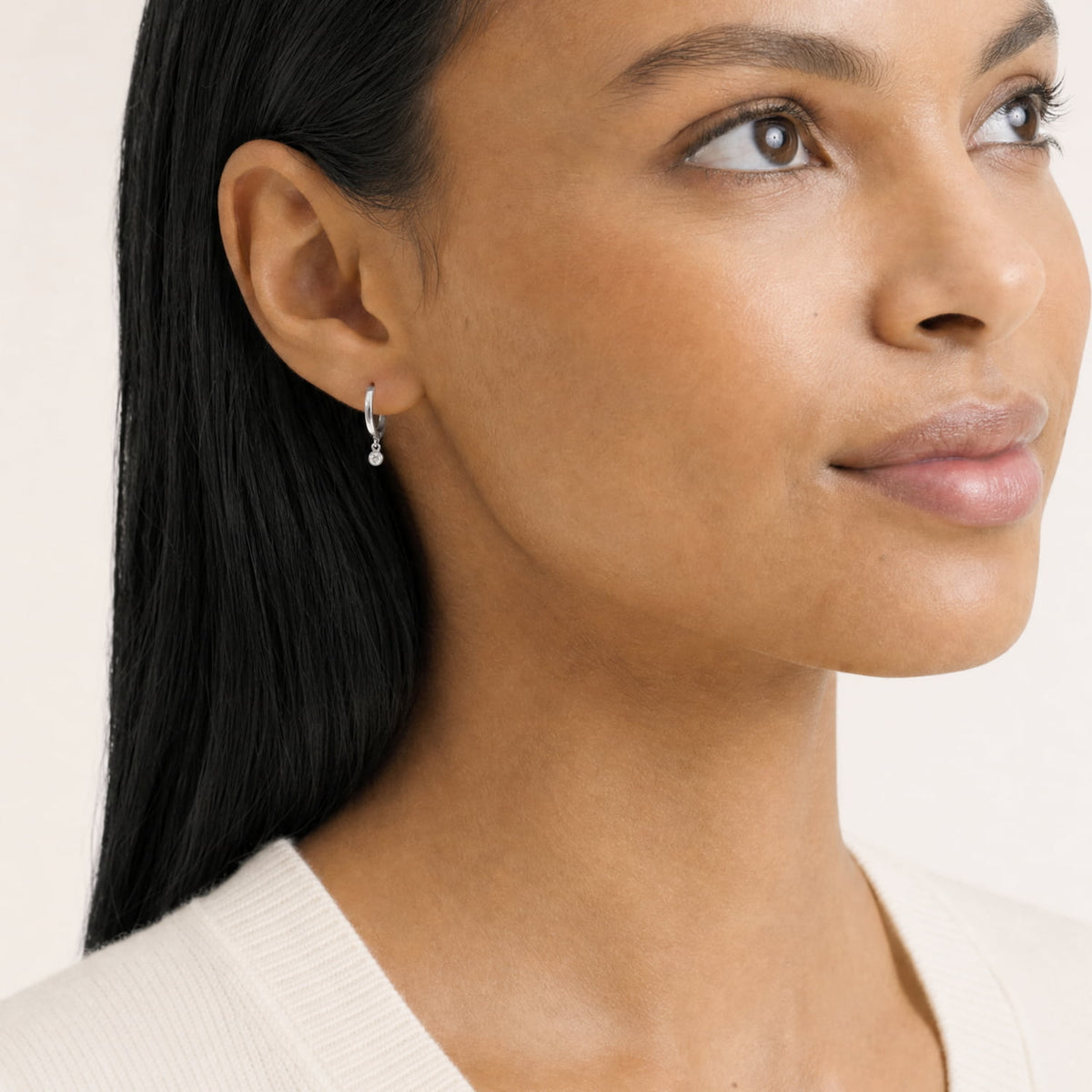 Model wears a pair of polished sterling silver hinged hoop earrings featuring delicate lab grown diamond charms that gently dangle, exemplifying sleek modern silver jewellery design.