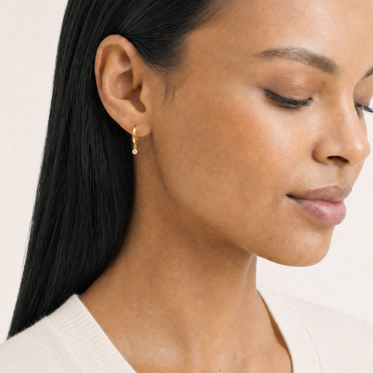 Model wears a pair of gold vermeil hinged hoop earrings featuring small round lab-grown diamond charms suspended delicately, showcasing a refined and sculptural luxury design.