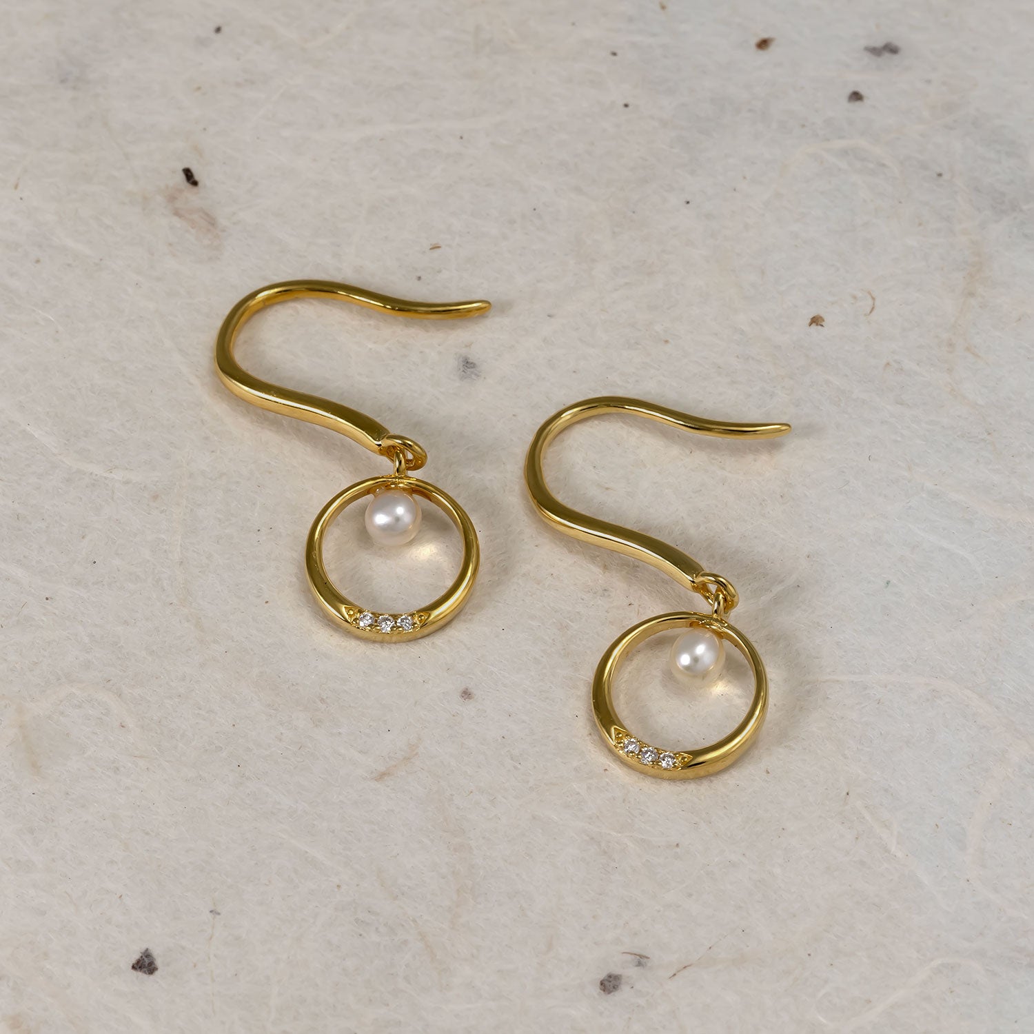 Elegant gold vermeil drop earrings featuring delicate freshwater pearls nestled within smooth circular frames accented by sparkling lab grown diamonds, designed for timeless style.