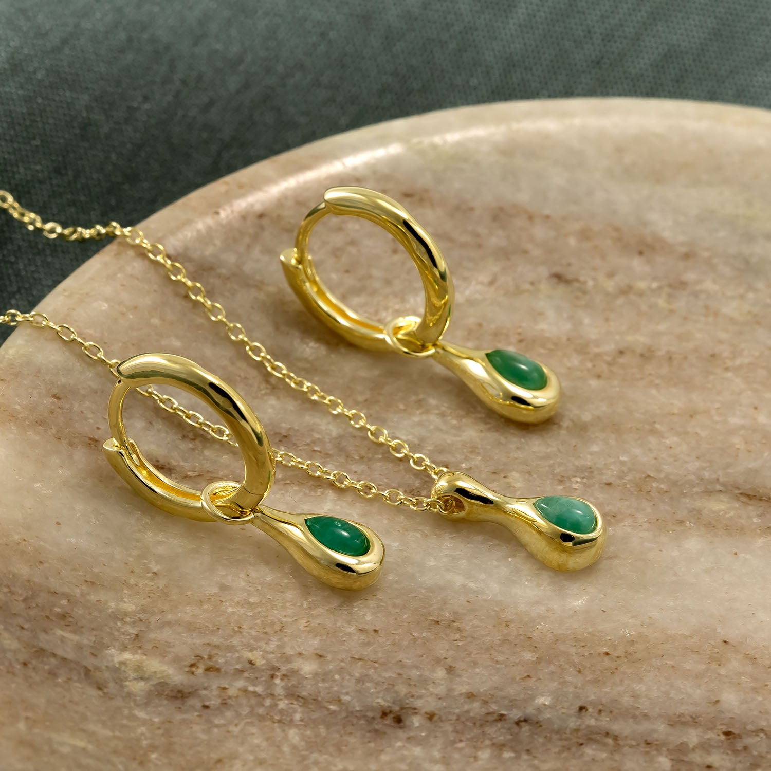 Pair of gold vermeil hoop earrings featuring drop-shaped amazonite gemstones alongside a matching pendant on a fine gold chain, displayed on a smooth stone surface.