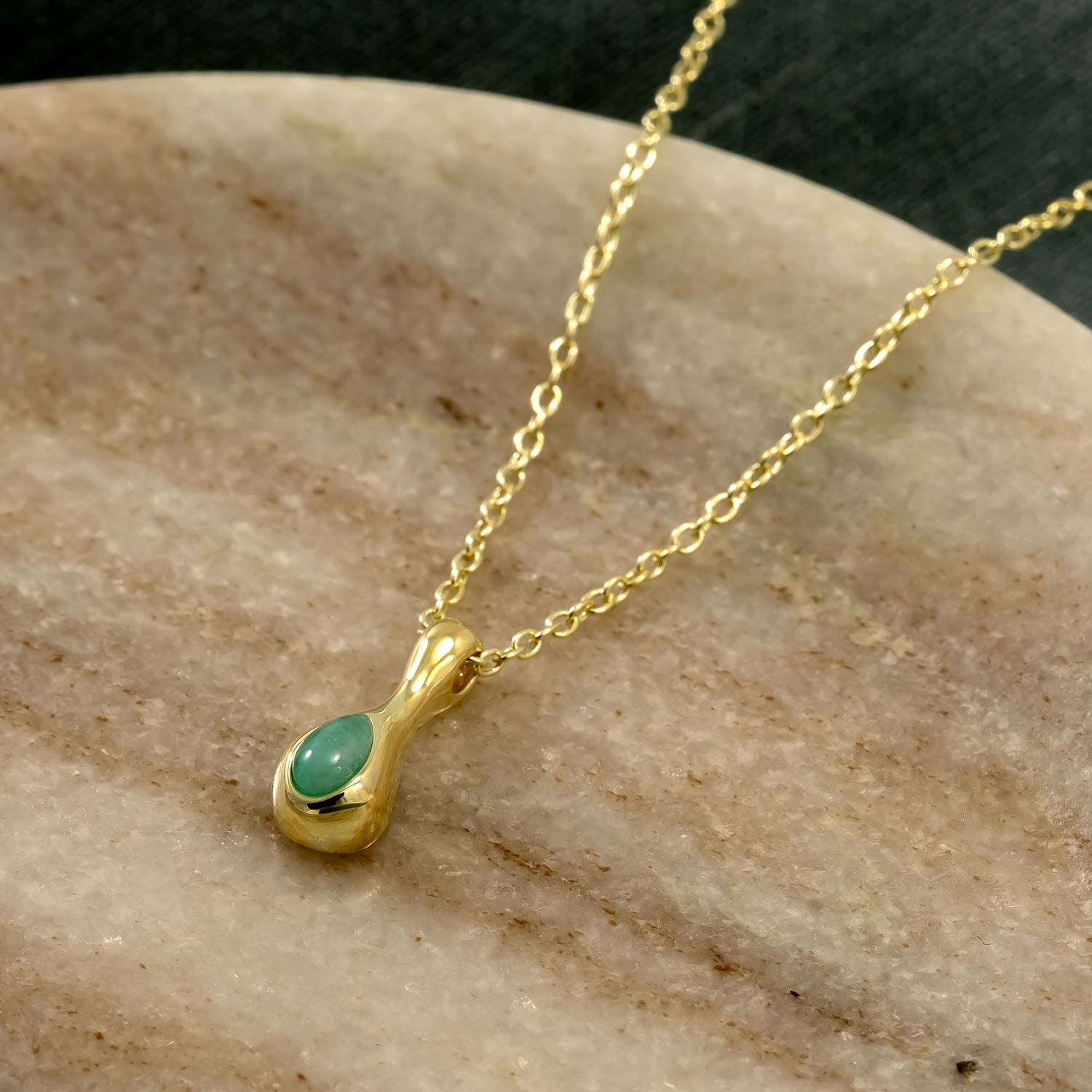 Delicate gold vermeil necklace featuring a smooth amazonite droplet pendant suspended from an adjustable fine chain, displayed on a neutral stone background.