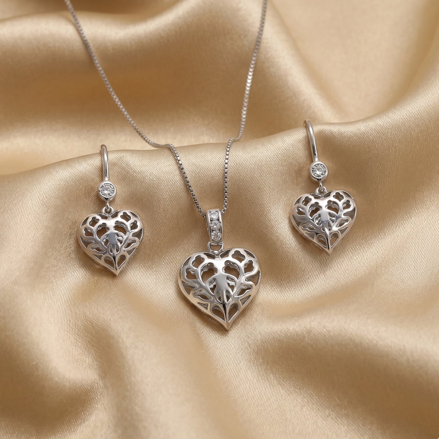 A pendant and a pair of Lab grown diamond and sterling silver drop earrings featuring delicate, sculptural hearts with intricate cut-out detailing, designed for elegant everyday wear.