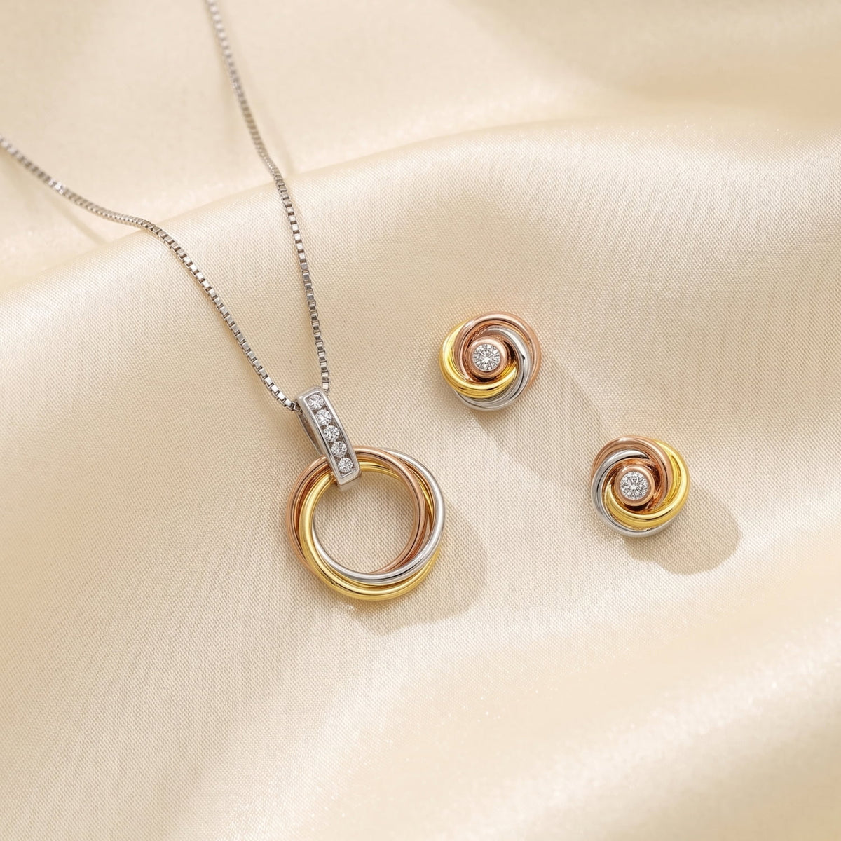 Pair of mixed vermeil gold and sterling silver earrings, and matching pendant, with intertwined love knot design, each set with a sparkling lab grown diamond for elegant fine jewellery.